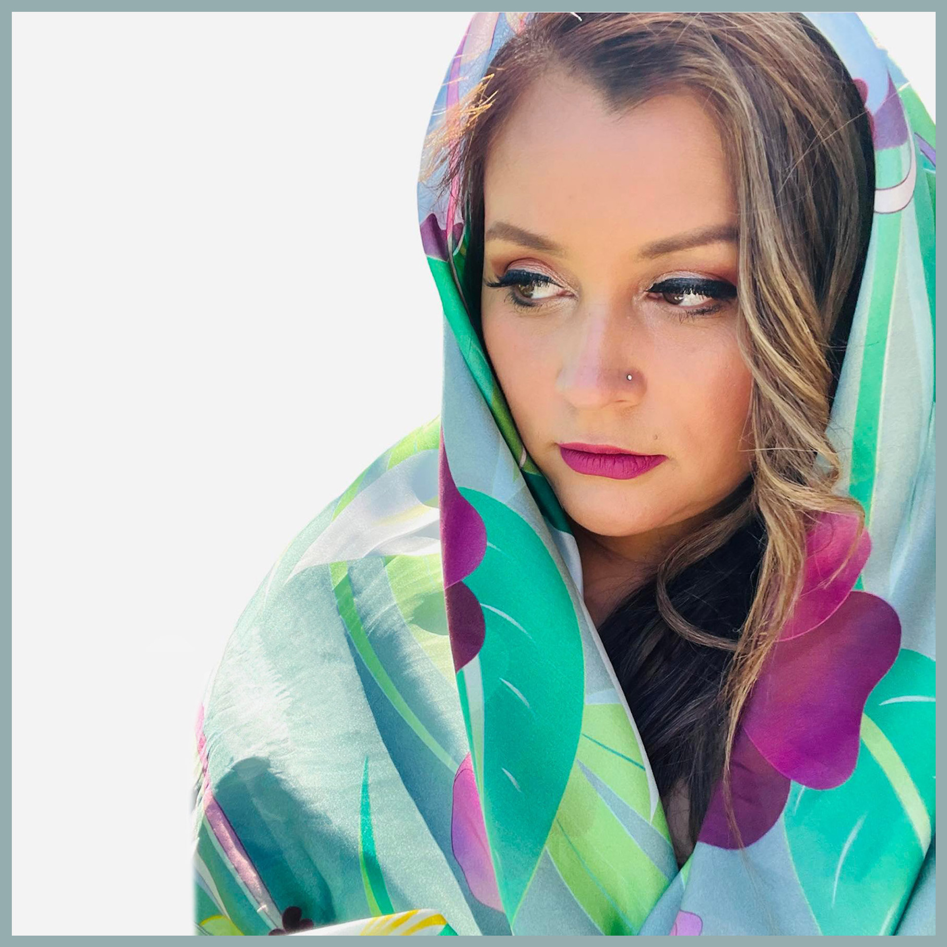 Woman wearing a floral silk scarf draped over her head.