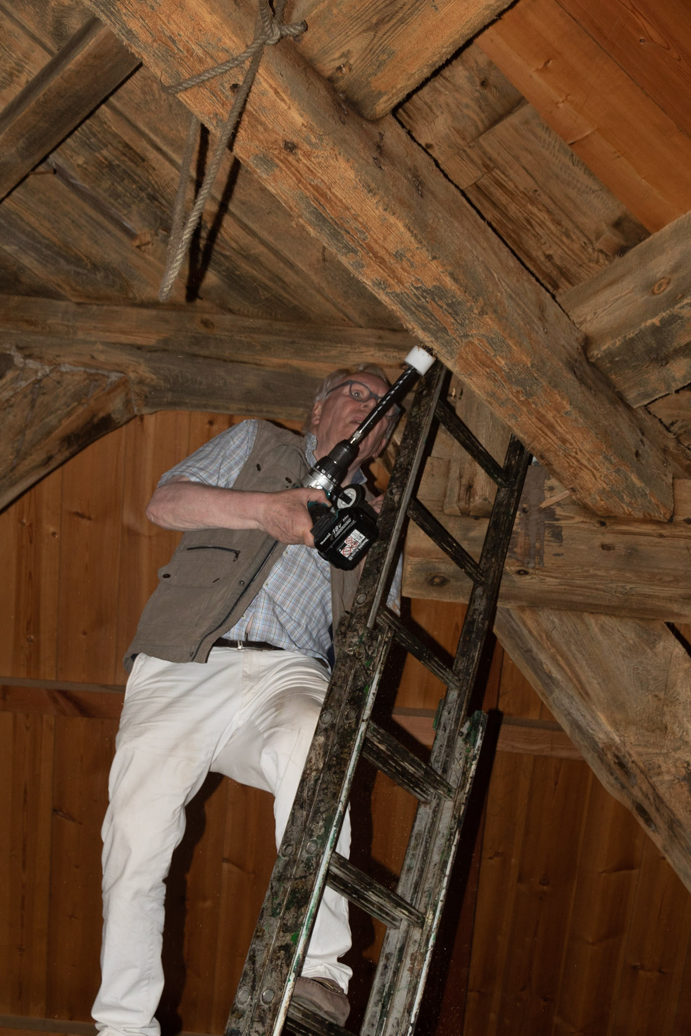 Soms wil je een slecht bereikbare balk dus boor je die bovenop een ladder, met de andere voet op een balk