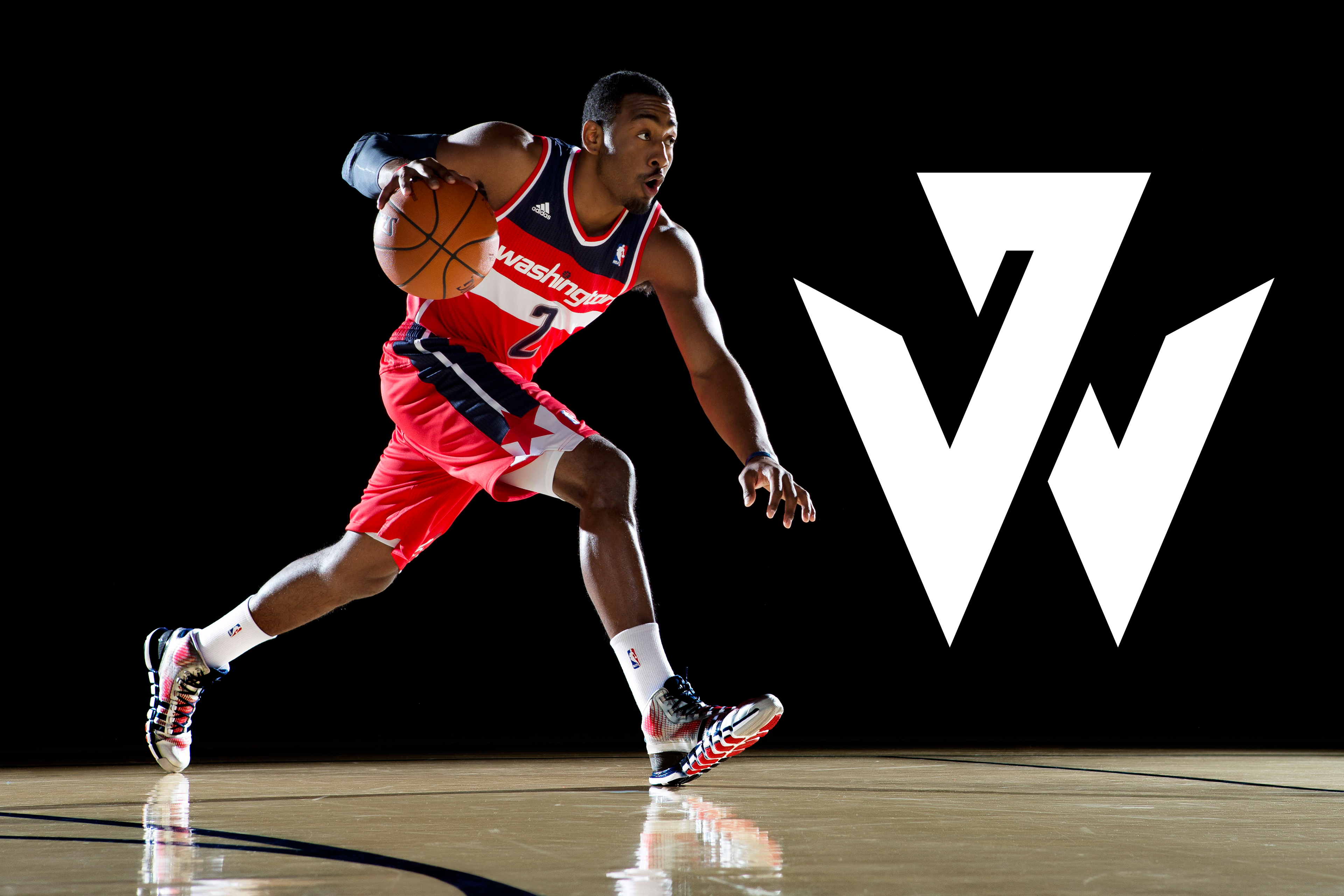 Photograph of John Wall dribbling next to large John Wall logo.