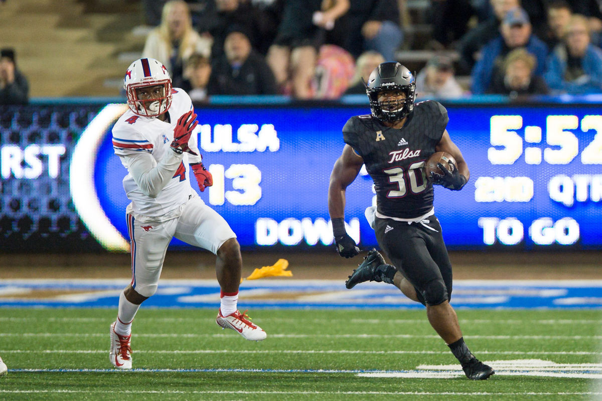 Photograph of football player running with the ball wearing new black alternate jersey adorned with new ID assets.