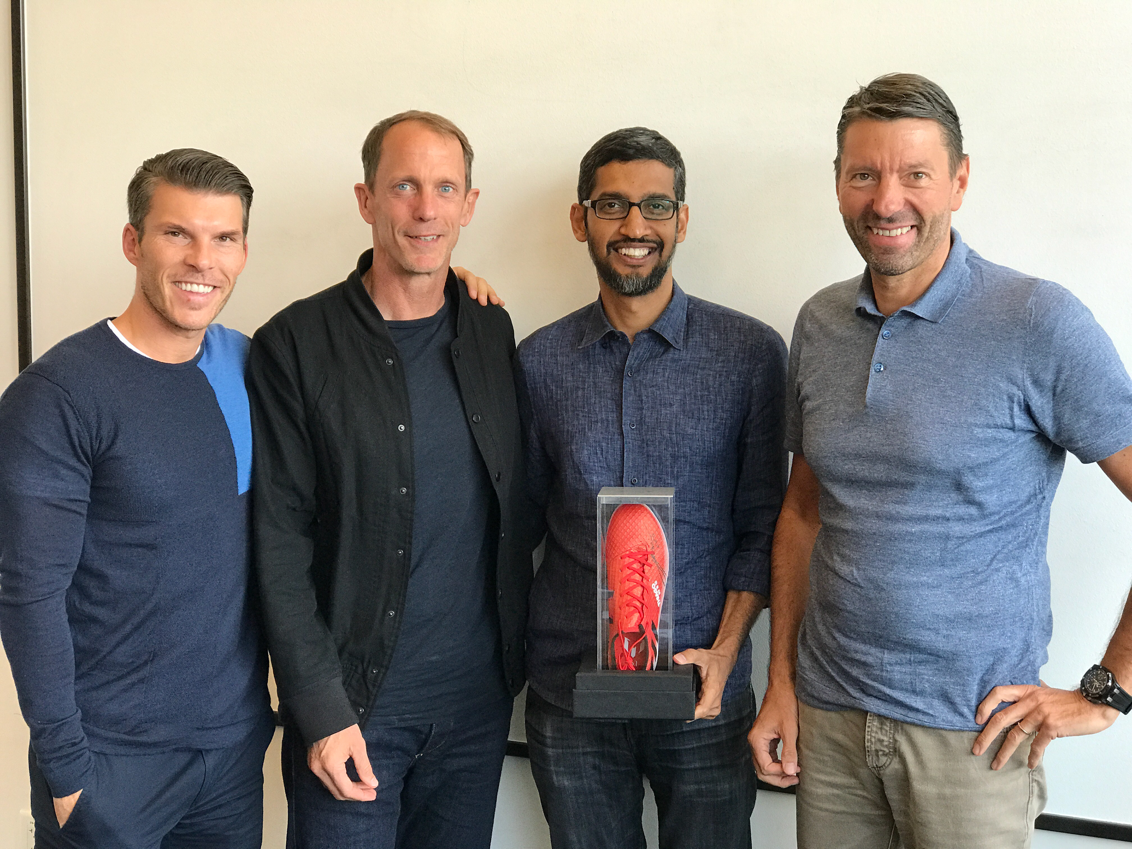 Photograph of Sundar Pichai holding the display case alongside notable adidas execs.
