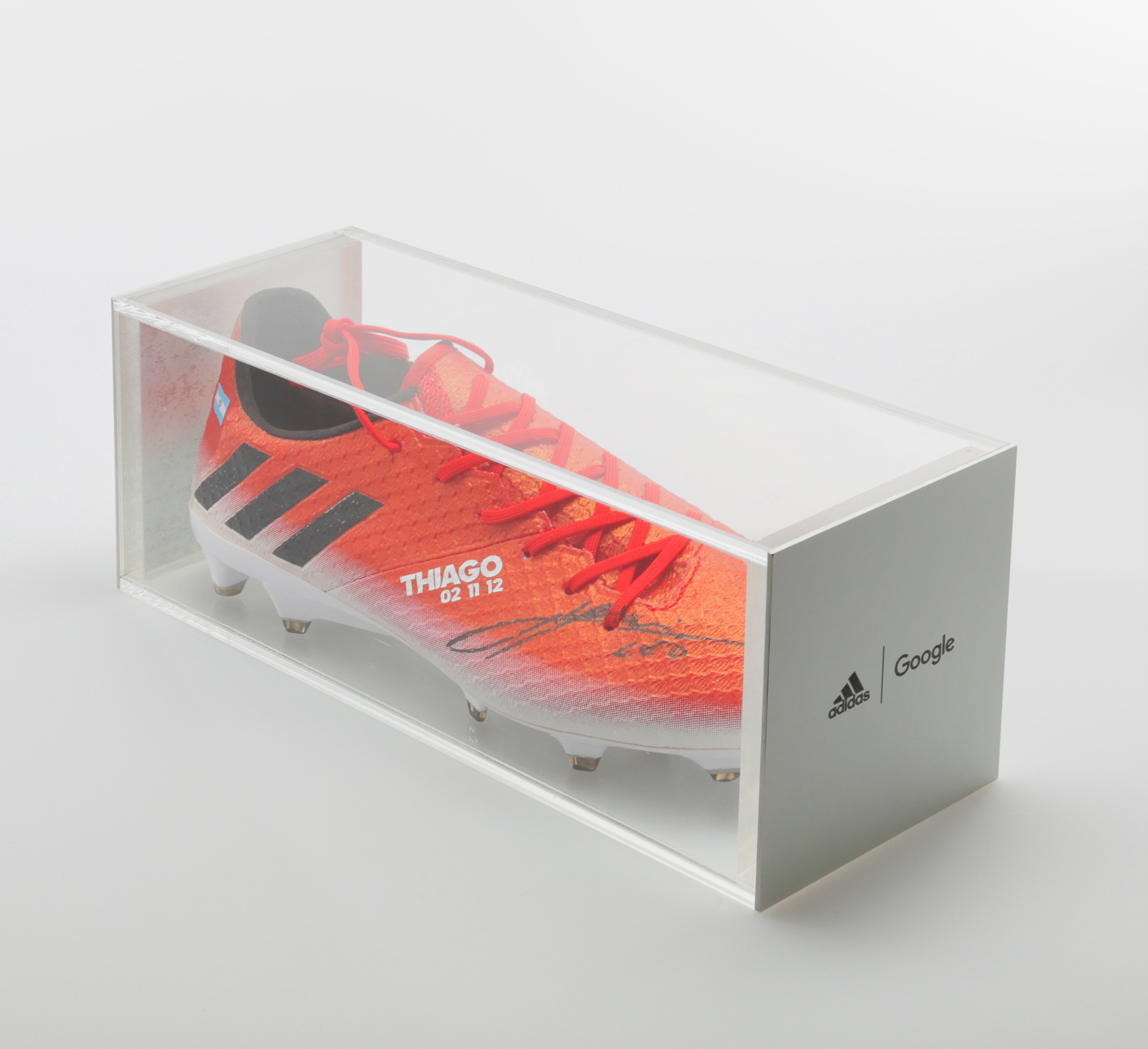 Photograph of shoe in display case with focus on the Messi autograph.