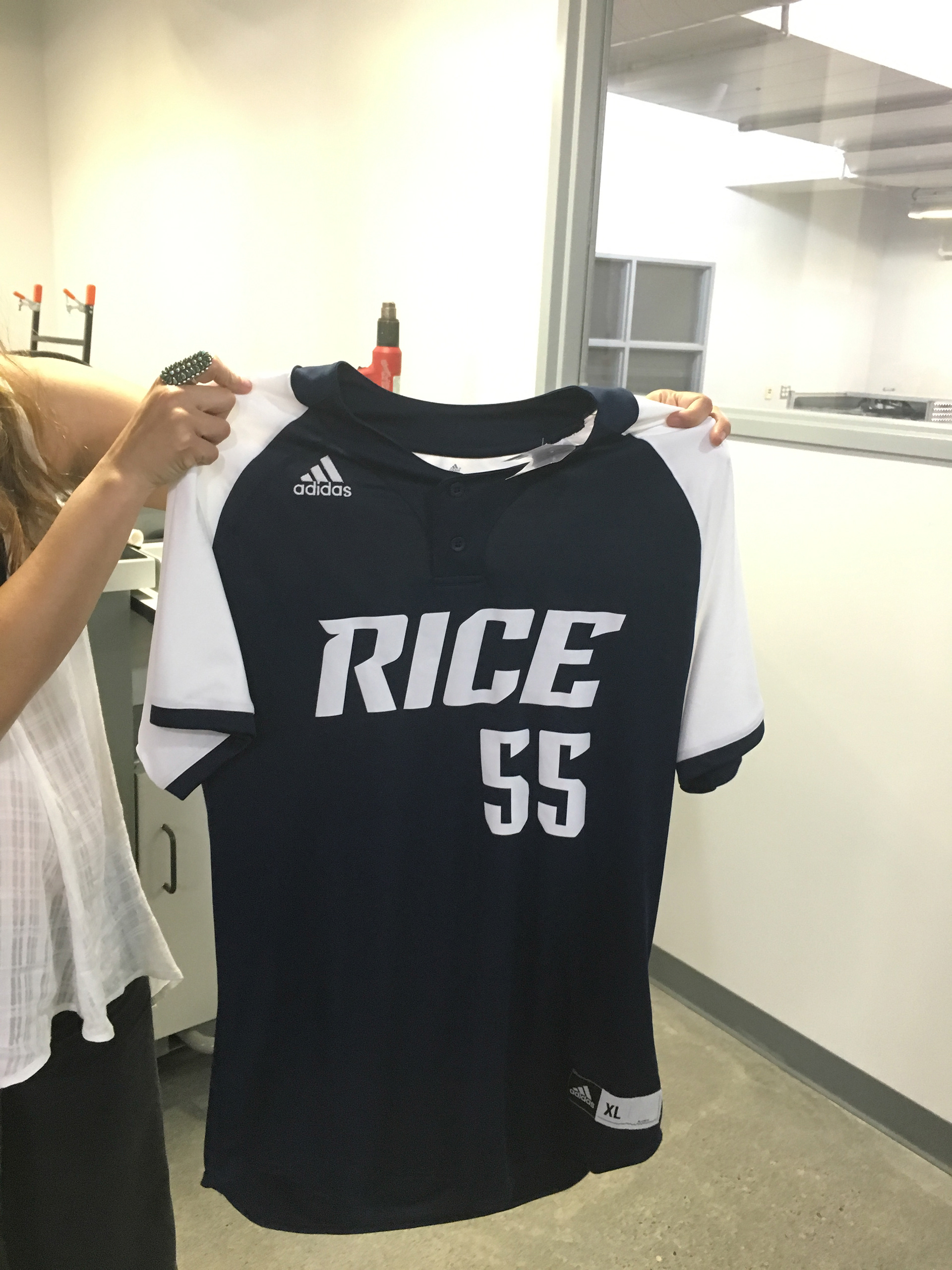 Photograph of woman holding up finished baseball jersey sample utilizing new wordmark and number system.