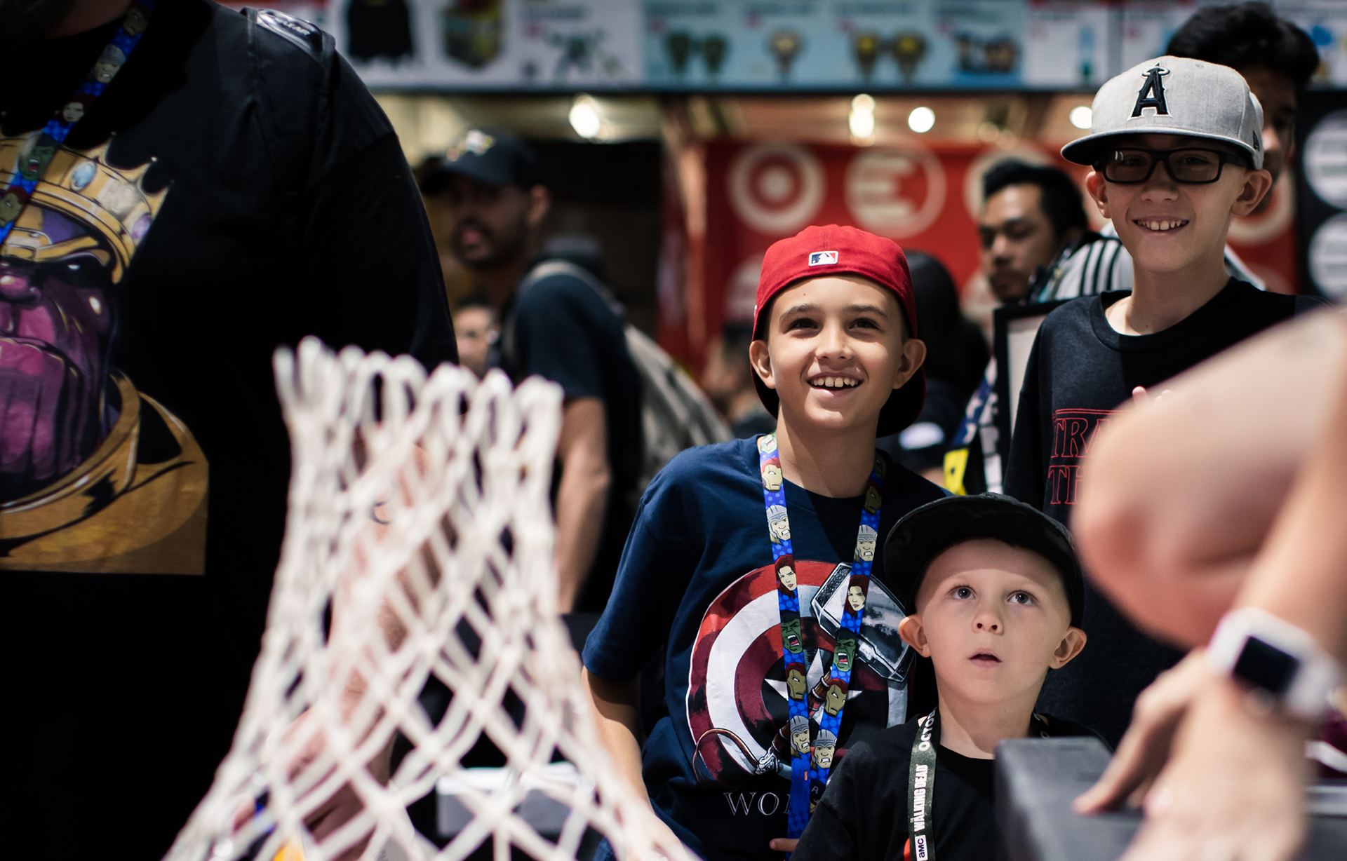 Photo of children smiling as they look at others having their photo taken at Comic Con Adidas x Marvel photo-op.