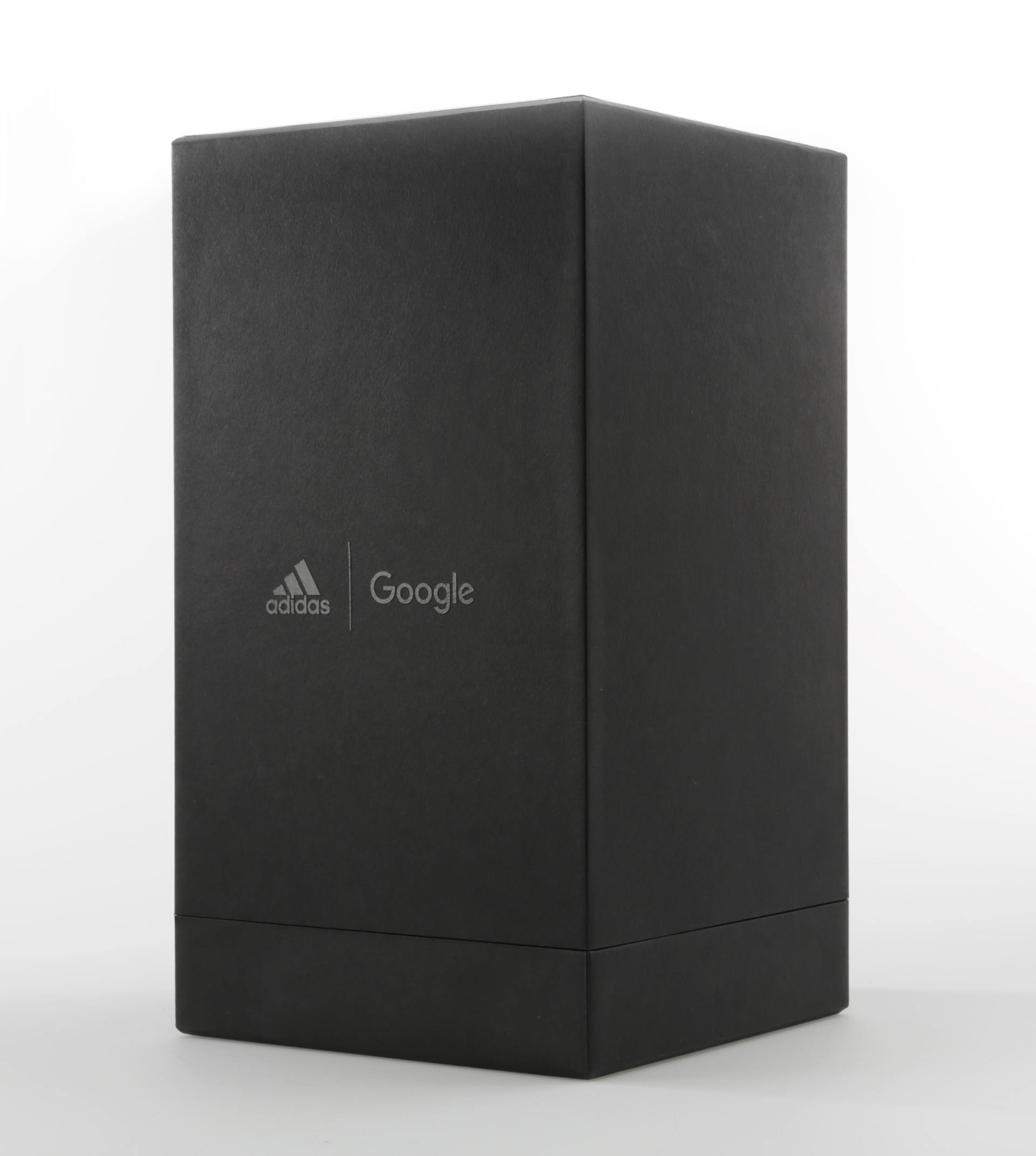 Photograph of final box standing upright with adidas x google logo varnish being highlighted through focused lighting.