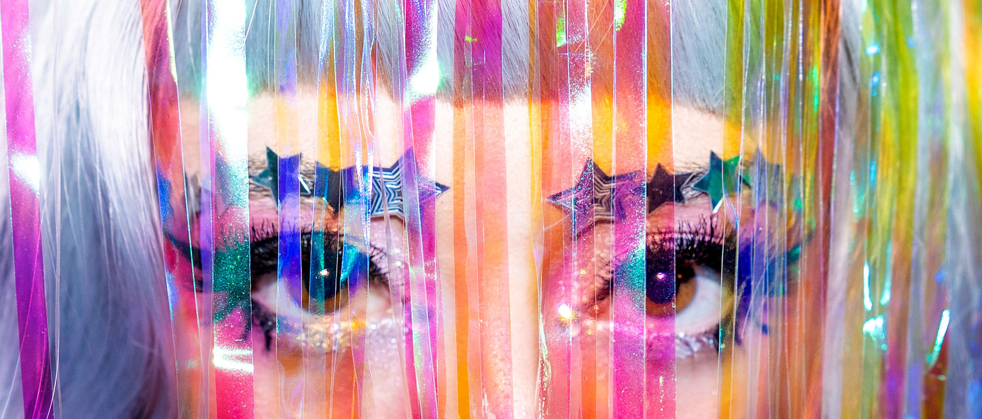Hannah Krause stands behind a tinsel curtain in Minneapolis, Minn. on June 26, 2024. Krause used this image for as a promotion for their backyard drag show.