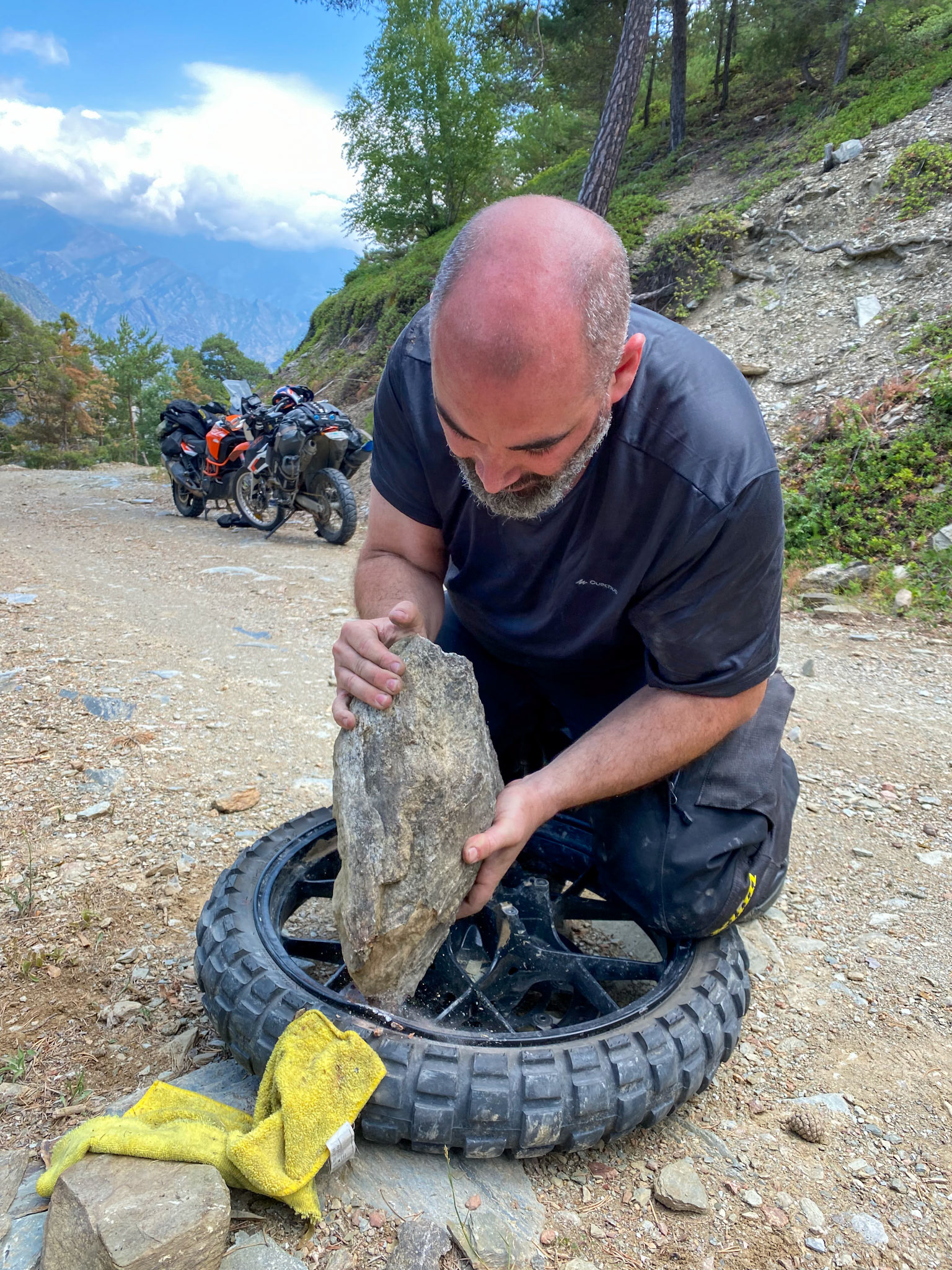 Soon after passing Alins, Vincent's front wheel hit a rock and lost its air. Here he is trying to bend back the rim.