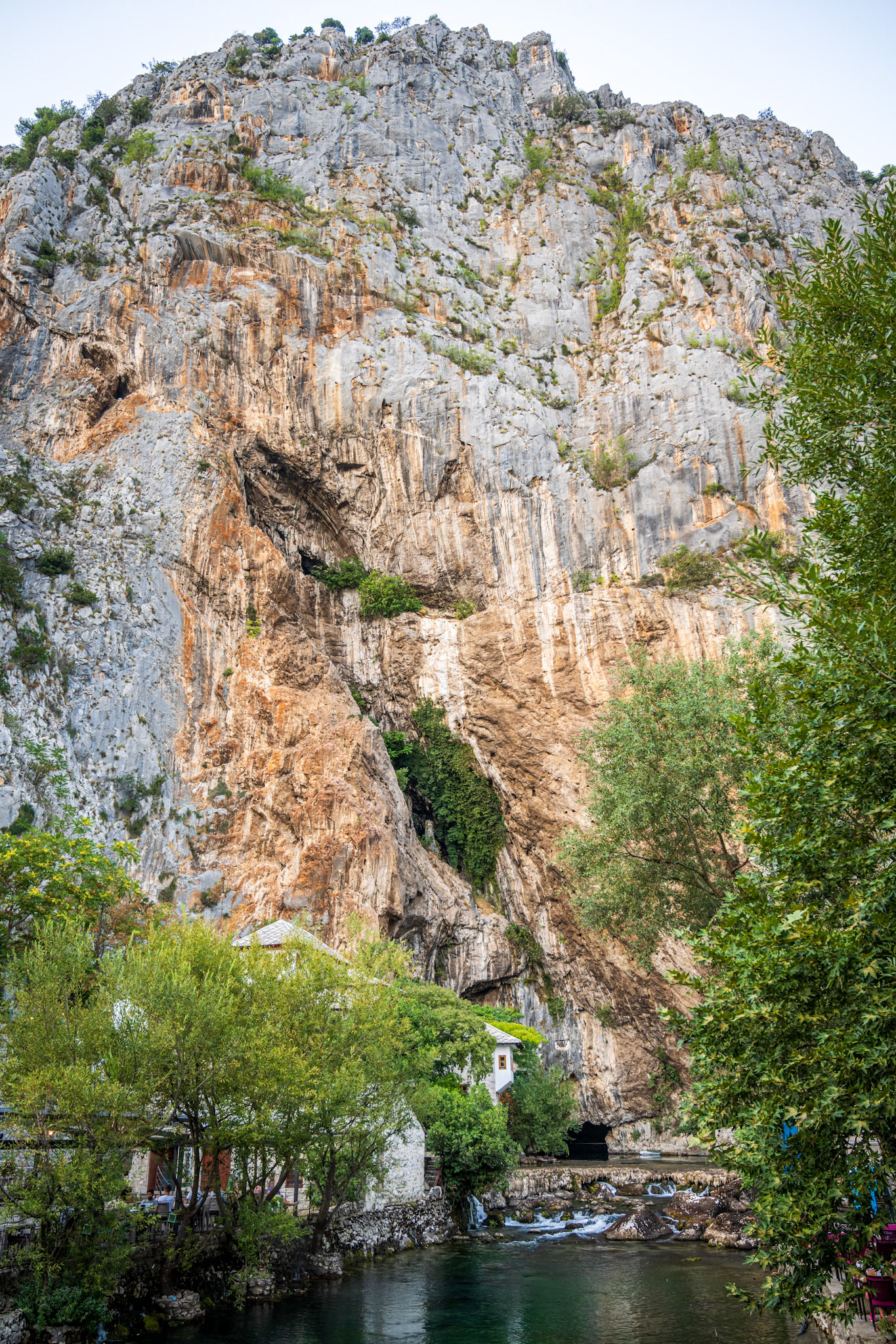 The cave at the bottom of a 250 m cliff hosts the spring of the Buna river, while the white building is the Tekija (Dervish House), from the 15th century.