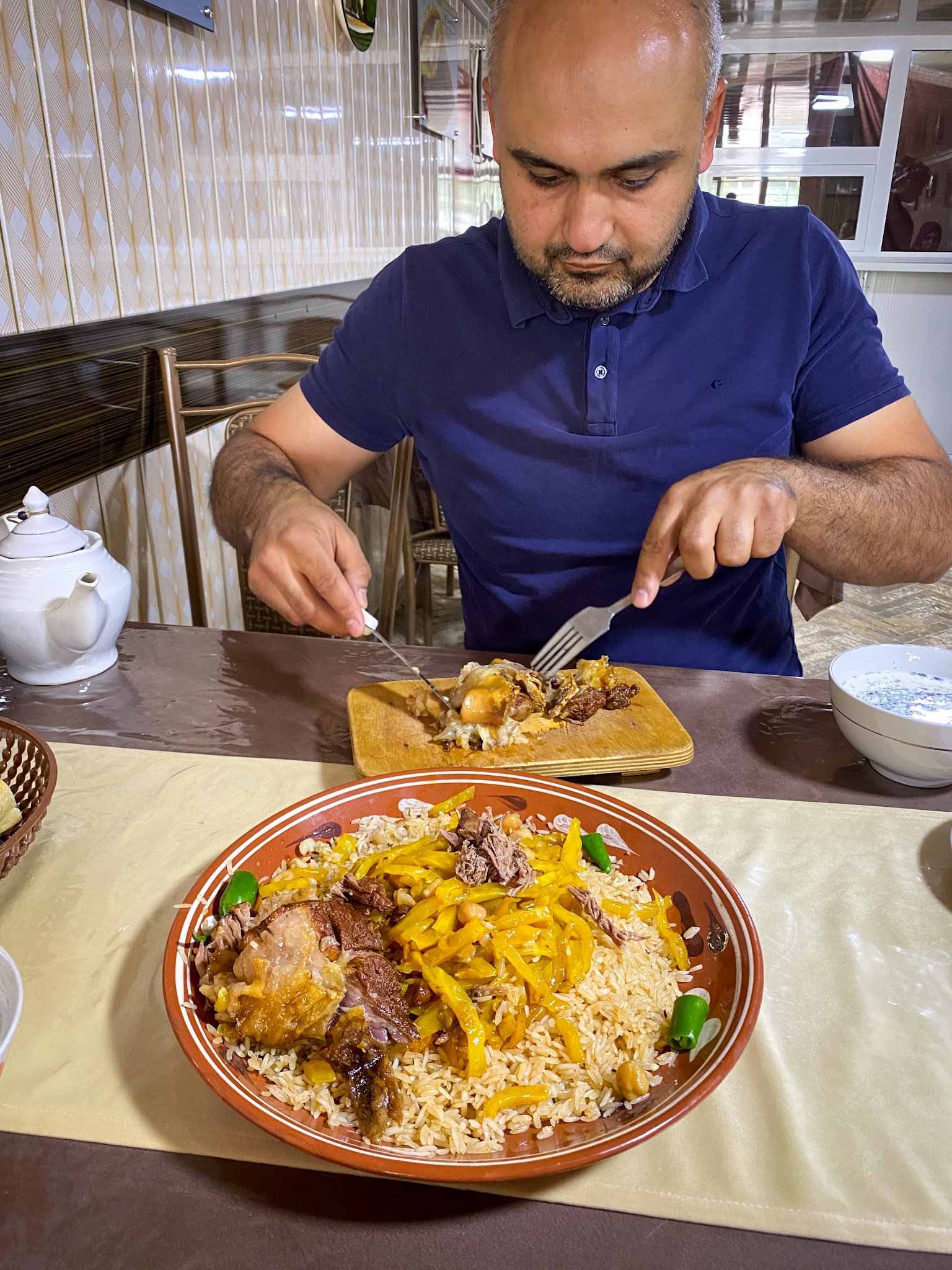 Aziz was so nice to take us for lunch and, despite our insistence, pay for it! They serve plov in a big plate and we all eat from it with a spoon. There is a small cutting board on the side where Aziz is removing the bones and skin of the pieces of lamb.