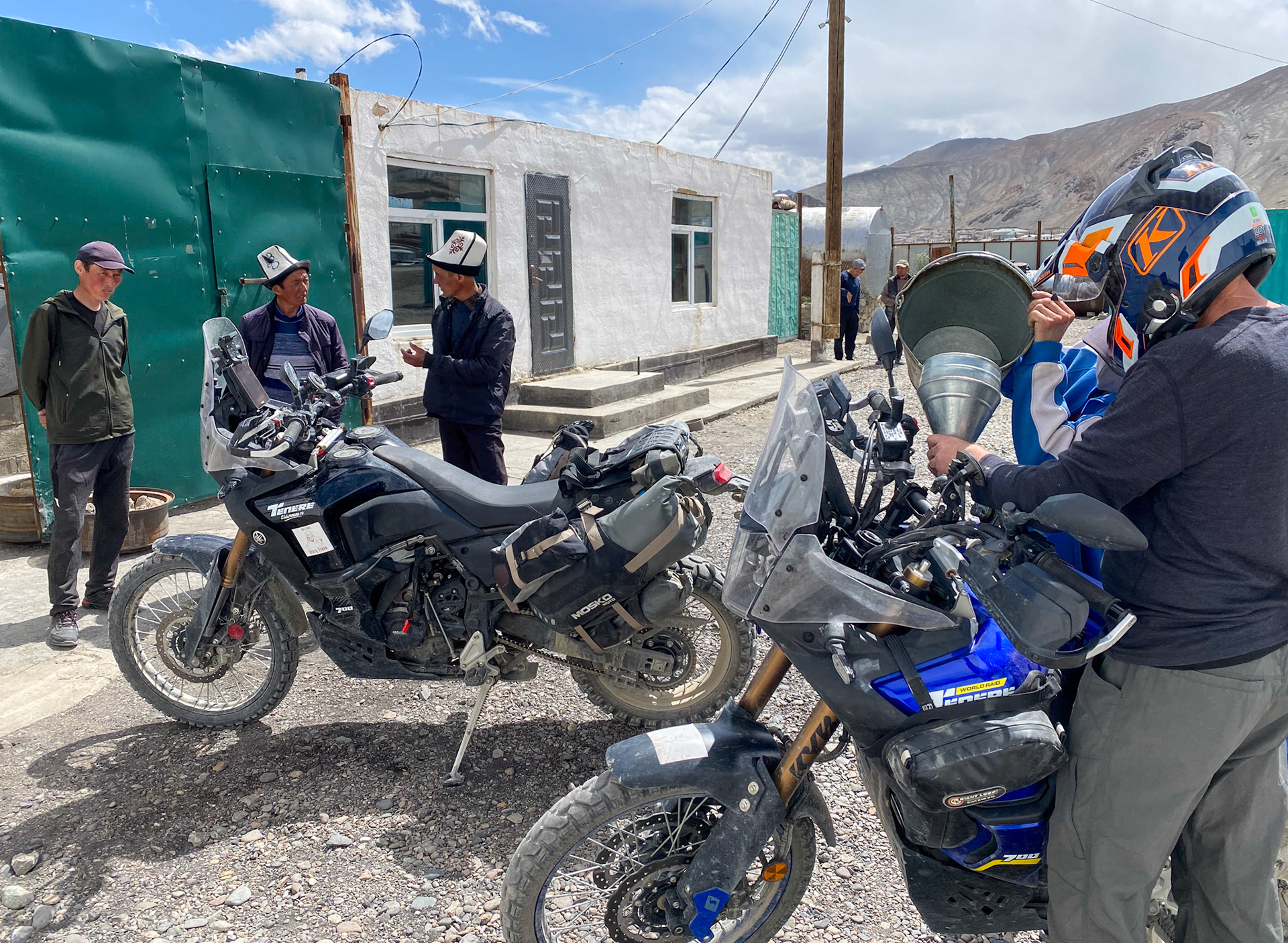 Getting gas from a bucket. The 2 men on the left wear the traditional Kyrgyz hat, the ak-kalpak, made of four pieces of white wool felt sewn together