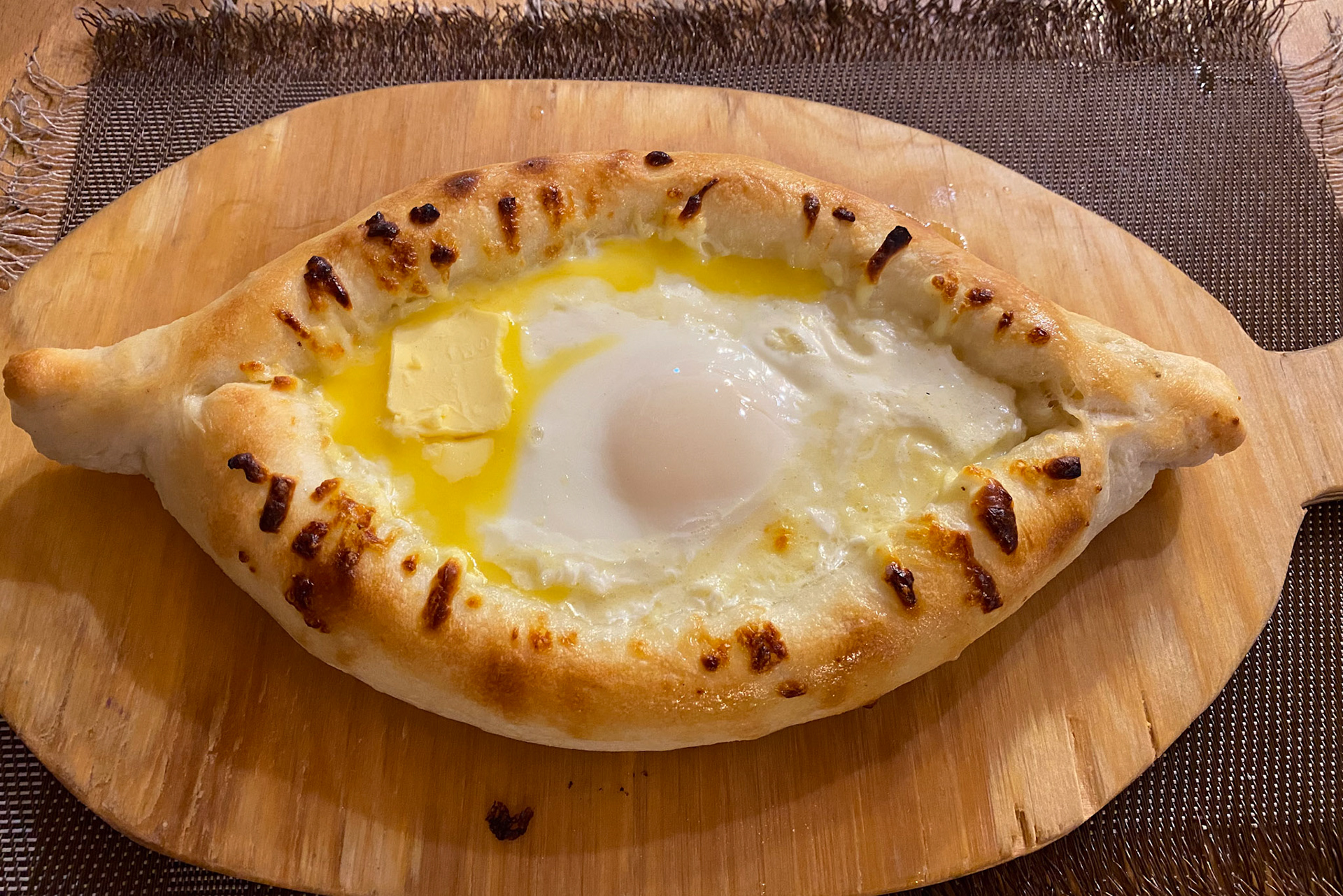 Adjaruli Khachapuri. As soon as it’s served, you have to swirl the ingredients togeth in er with your fork until the egg and butter are completely blended with the mass of cheese. Then tear a piece of the bread and dunk in!