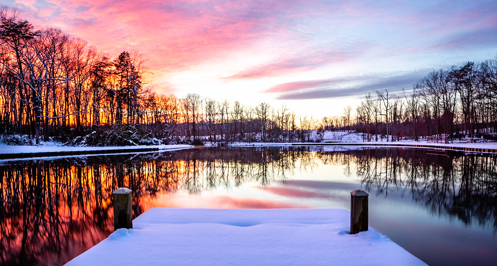 A beautiful colorful sunset in January, a pond and snow covered ground
