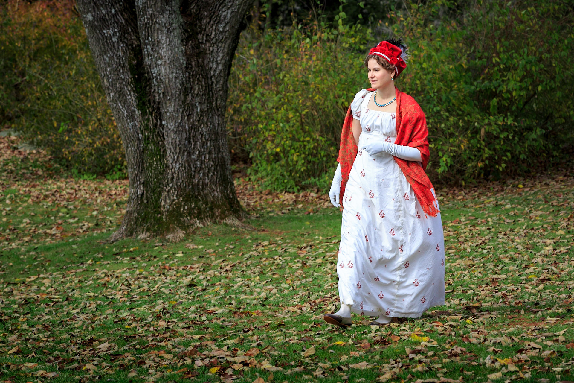 Woman dressed as Mrs James Monroe walking, red hat and red shawl
