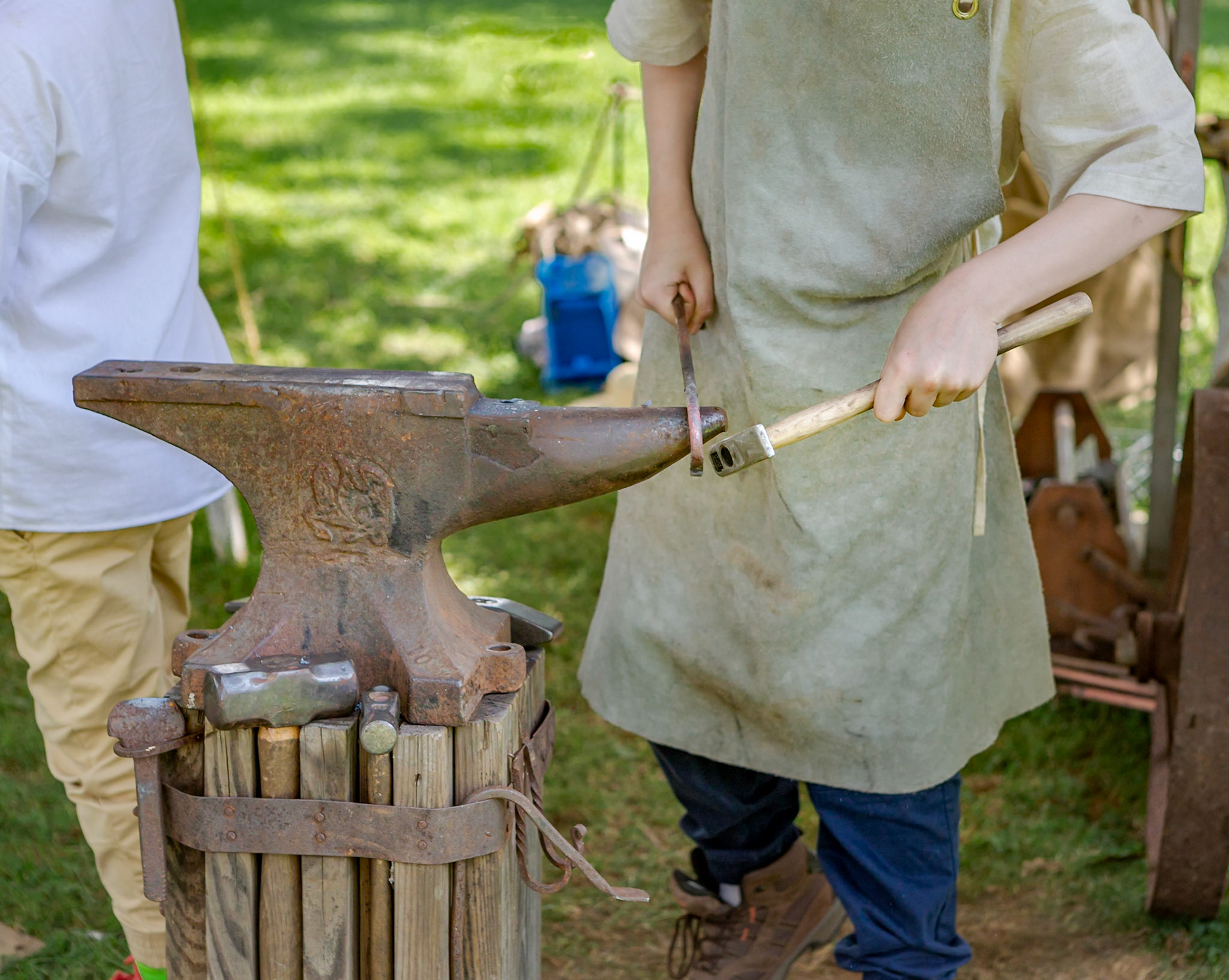 A young blacksmith forming a hook with a hammer and anvil