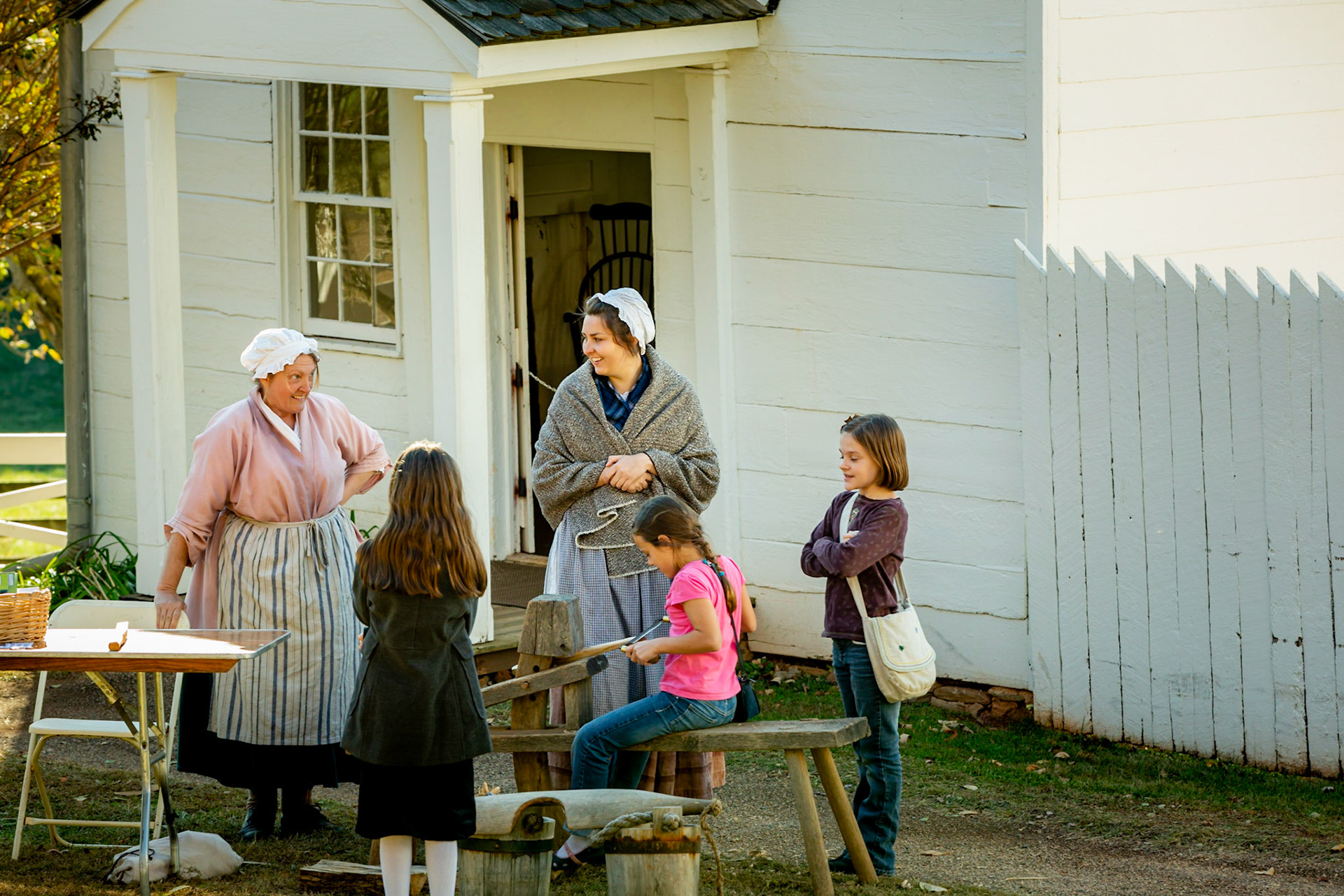 Women demonstrating to young girls how things were done long ago.