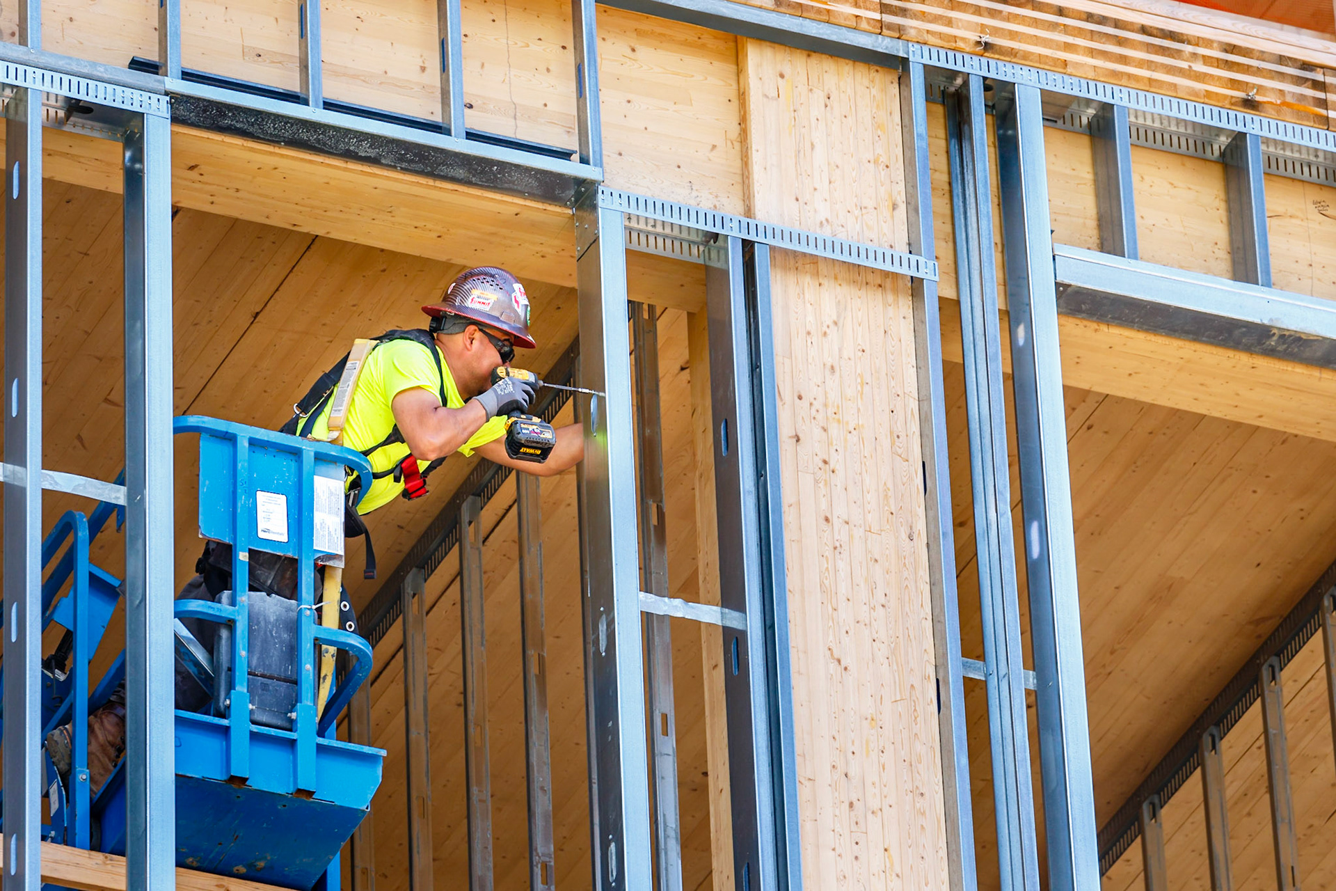 Construction worker attaching metal studs to a cross laminated timber building