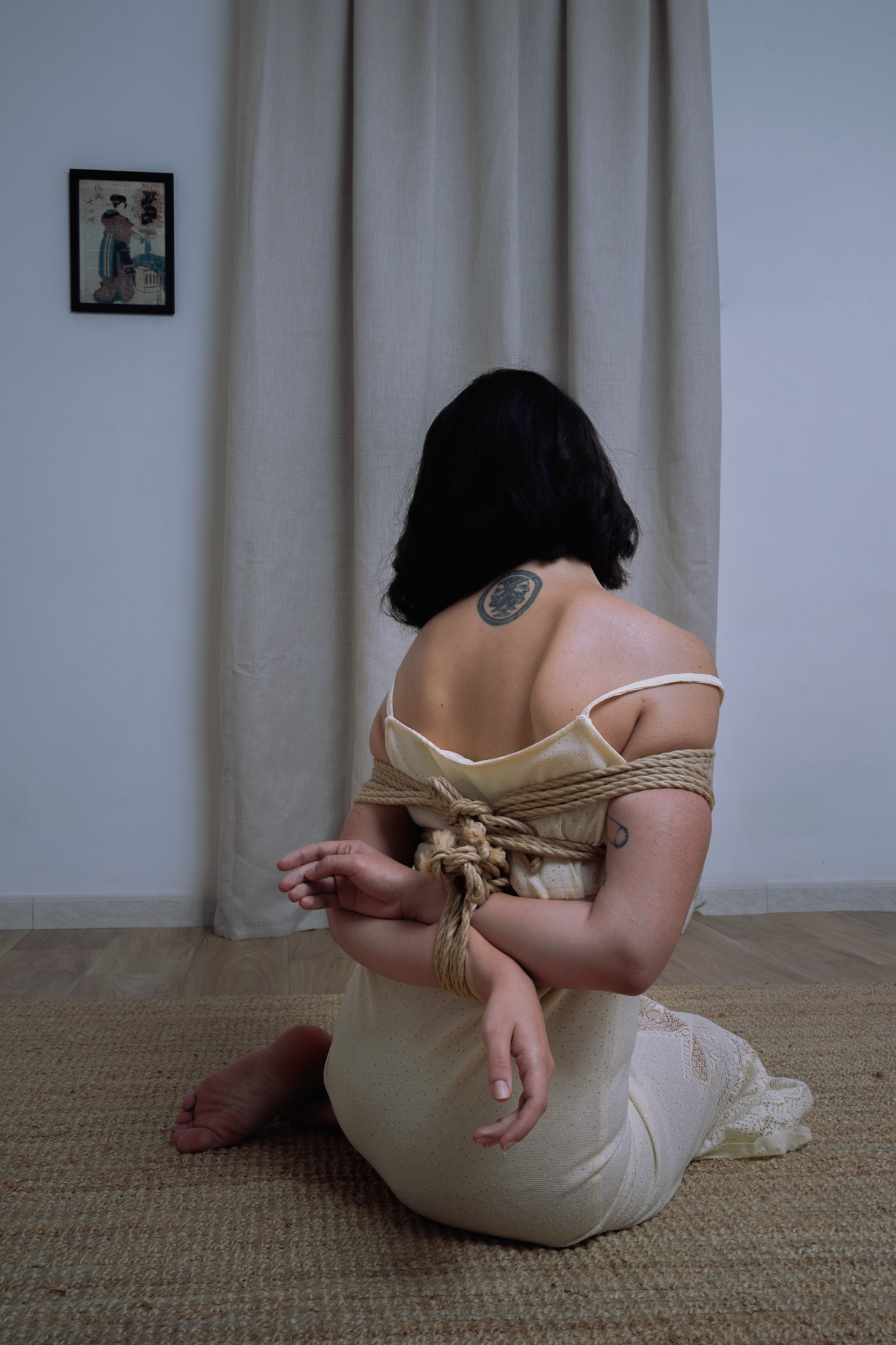 Una donna ripresa di schiena, legata con corde da shibari e illuminata da una luce delicata, nel progetto «Corde e Silenzio».