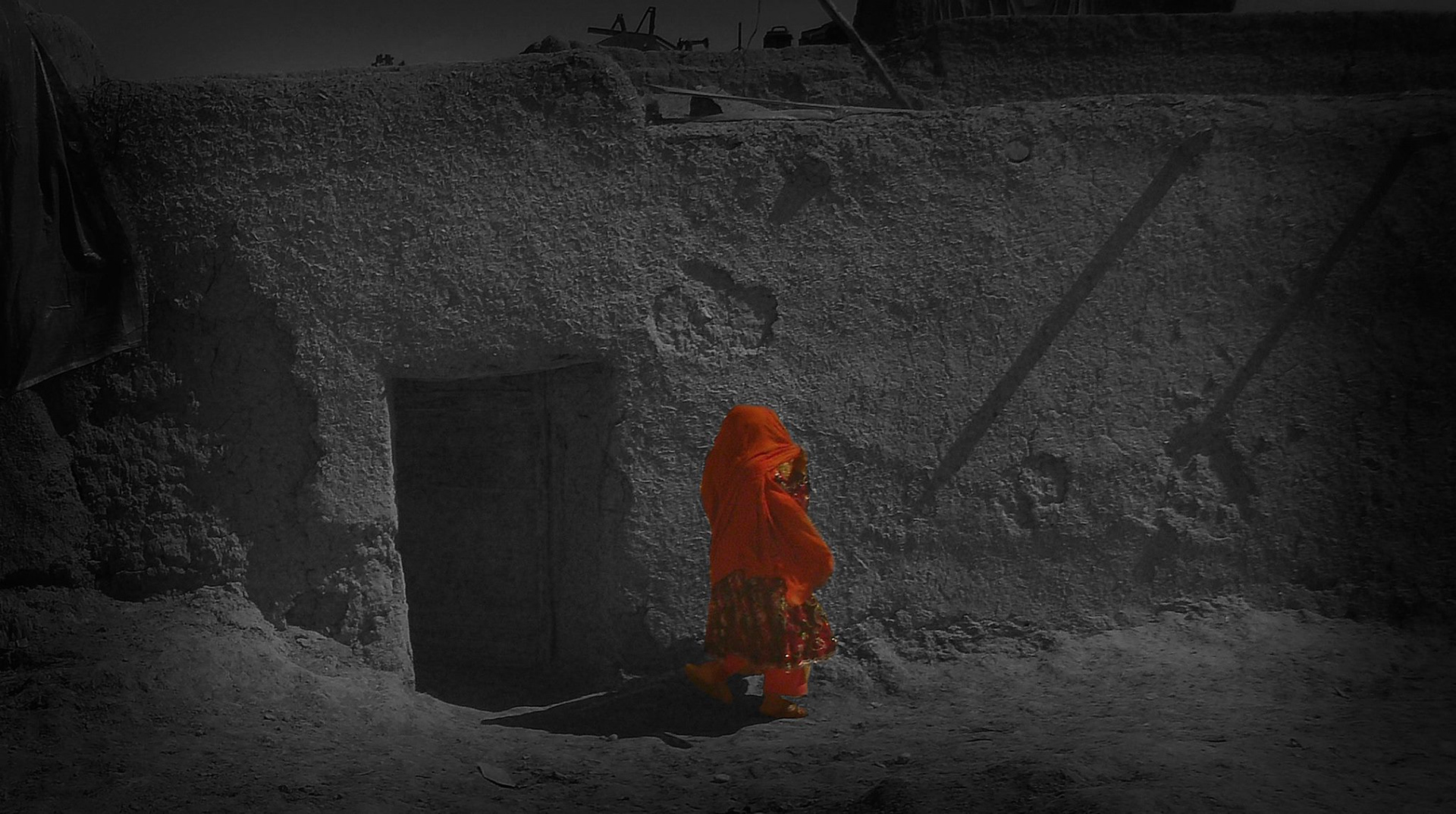 #3 Afghan Woman, 2011, Photo captures an Afghan woman highlighted in red against a desaturated home to focus on the subject.