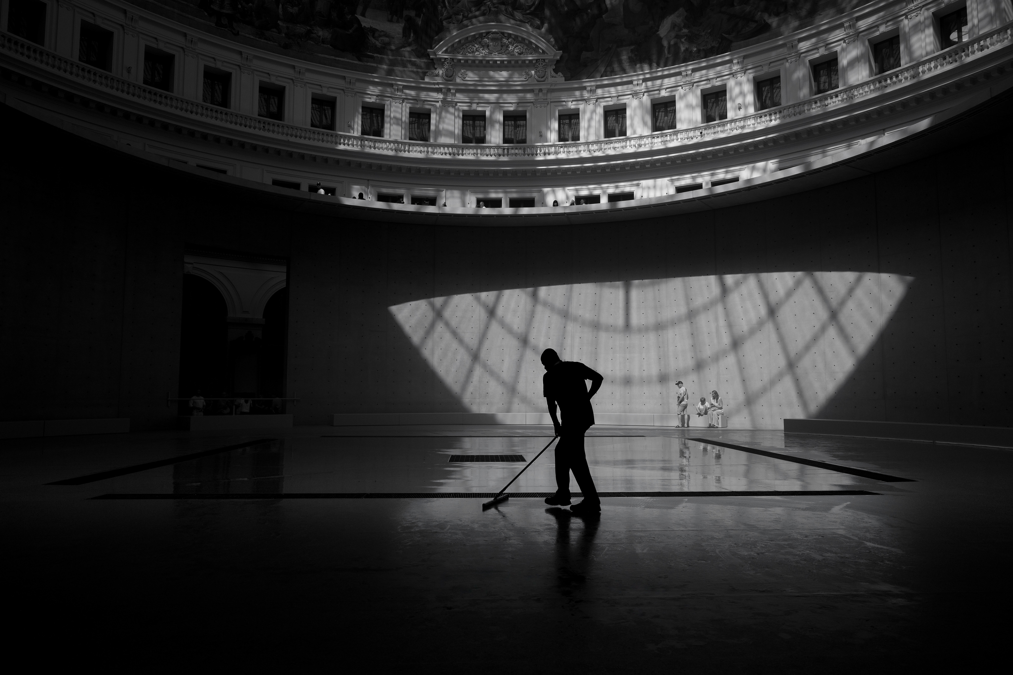 A cleaner sweeping the floor beneath the dome of the Bourse de Commerce