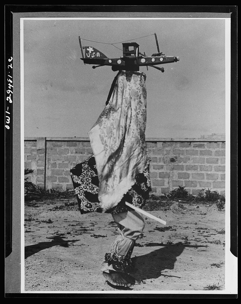 Somewhere in Central Africa. Here, at length, is the witch doctor and his USA airplane, the P-40 or „steam-chicken” as the bushmen call it. Civilization advances into the inner sanctums of the medicine men, and penetrates the Dark Continent, which for hundreds of years held to tribal masks passed down from generation to generation. Supplanting it with the stronger ju-ju of the white man, the medicine men construct these planes, complete with antenna and the U.S. star, and descend on the tribe in flying echelon, as the evil spirits of the Nazis are driven out of the black man’s territory. https://www.loc.gov/resource/fsa.8d29874/