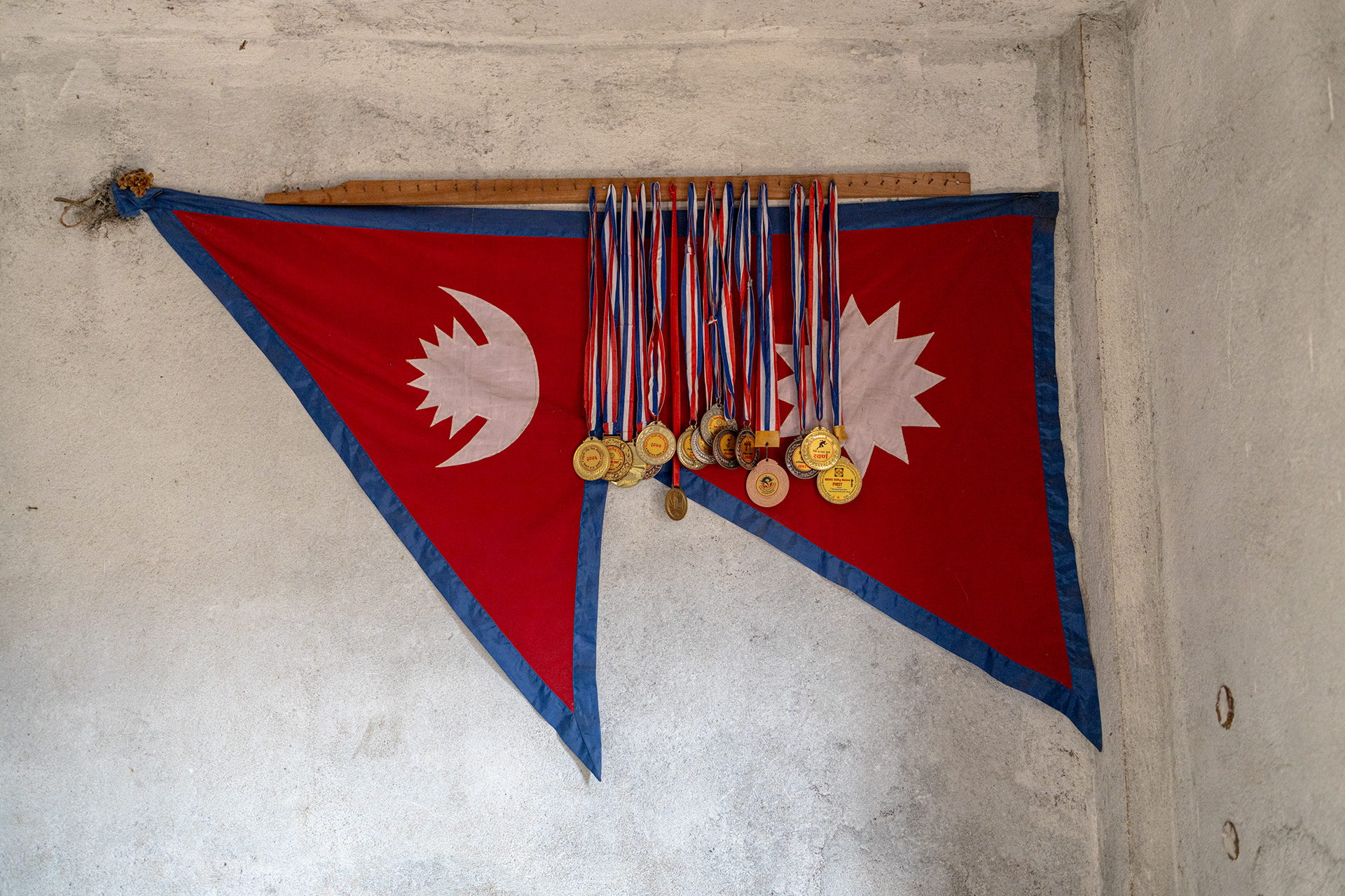 Medals belonging to Dinesh Rai, a young Nepali athlete who was killed near Bakhmut after joining the Russian army. The Nepali flag displayed in mourning hangs inverted.