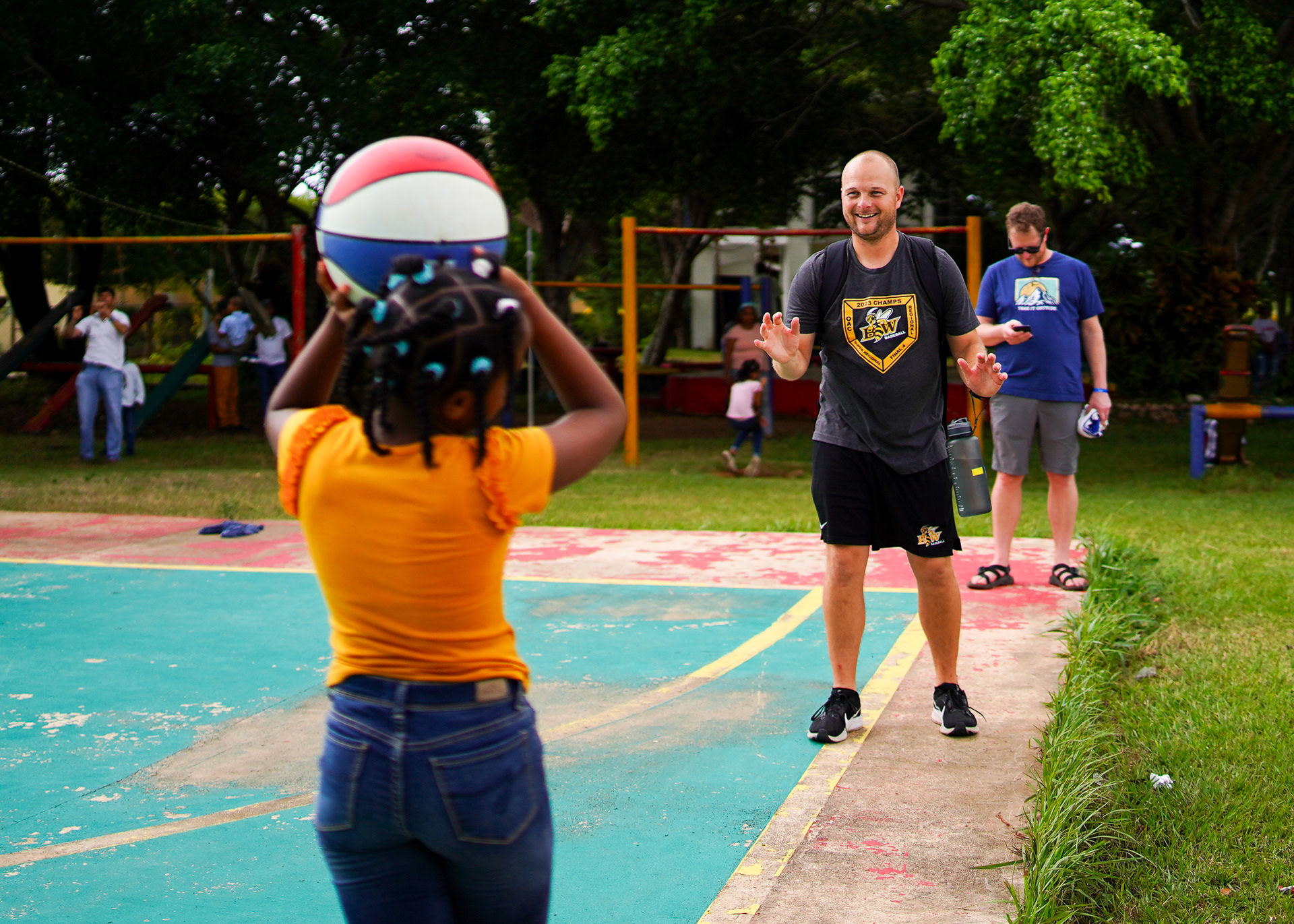Associate Head Coach Rosinski plays catch with a young girl at the orphanage.
