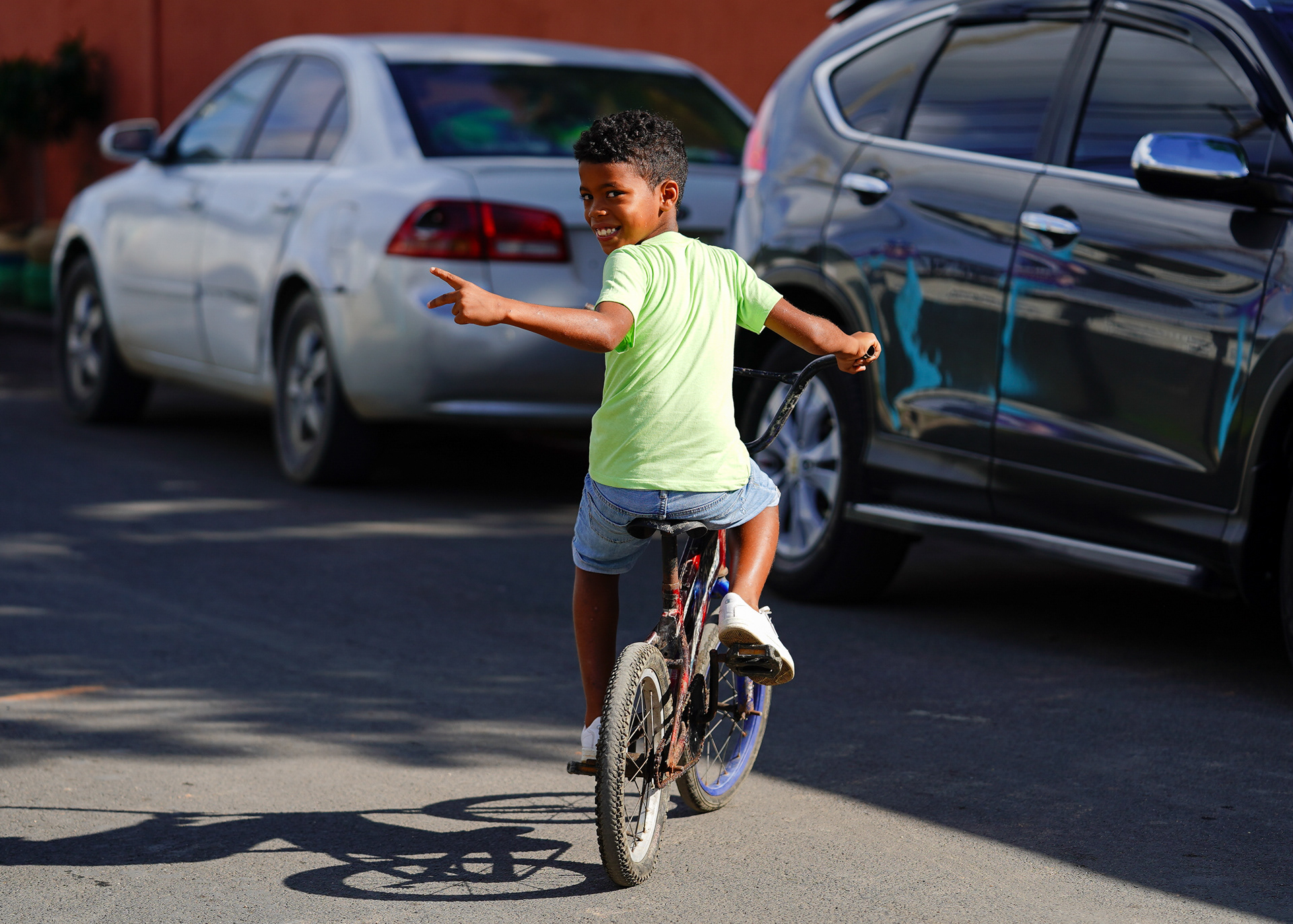 A local boy smiles while posing while riding his bicycle.