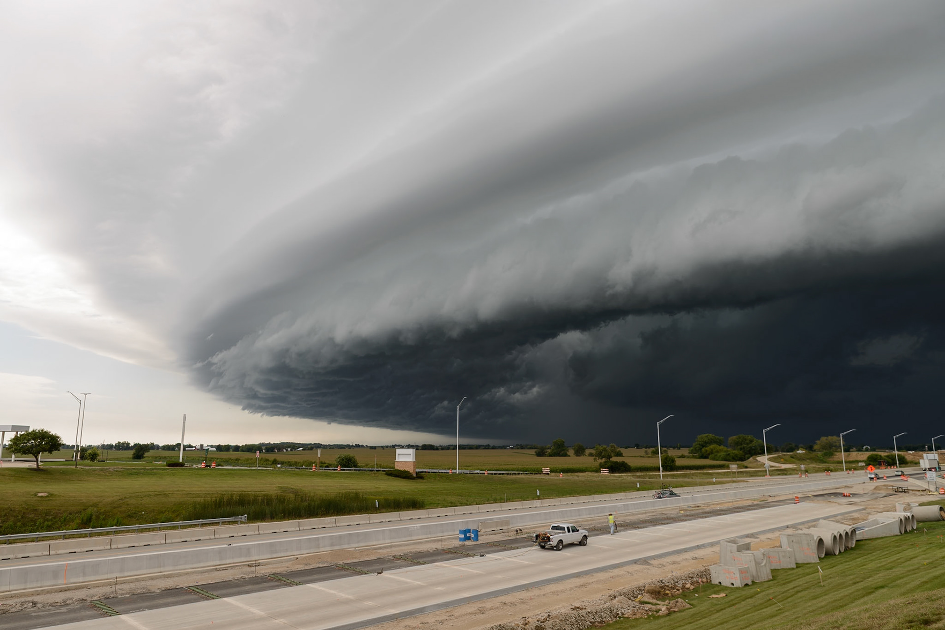 An ominous shelf cloud, the leading edge of a severe thunderstorm, dwarfs a highway construction project in Belvidere, Illinois. These low-hanging arcus clouds often precede a storm's powerful gust front, signaling the arrival of strong winds.