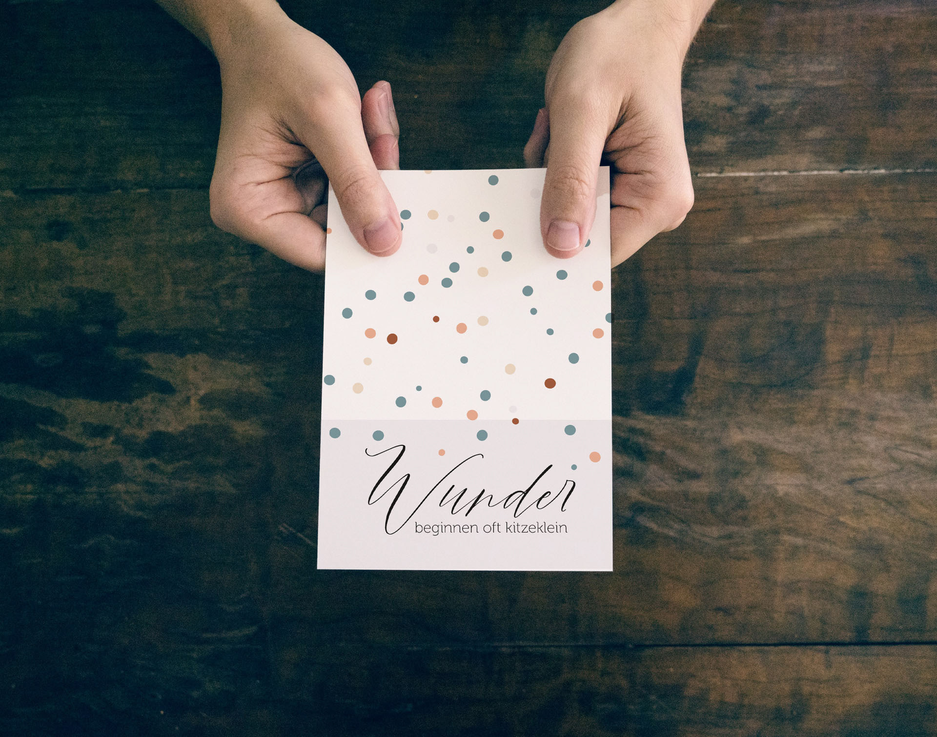 Karte zur Geburt, minimalistisch gestaltet mit verschieden farbige Punkte in mehreren Größen. Im unteren Drittel ist ein grauer Balken mit dem Text: Wunder beginnen oft kitzeklein