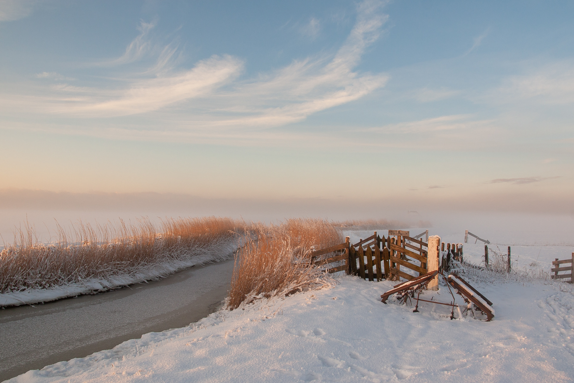 De besneeuwde polder van Noord Holland tijdens het laatste licht op een mooie winterdag.