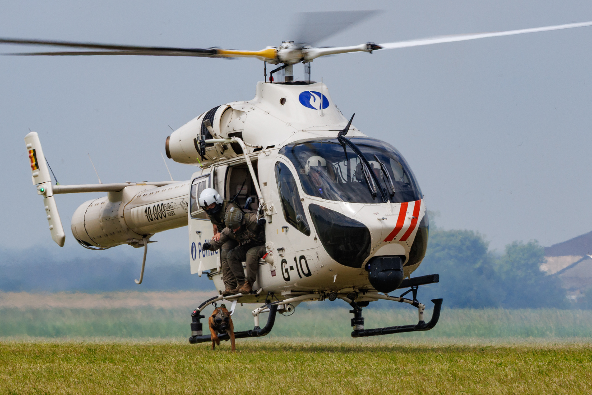 Belgische Politie MD-902 Explorer helikopter (G-10) waarbij een politieagent met een politiehond uit de helikopter stapt tijdens een demonstratie.