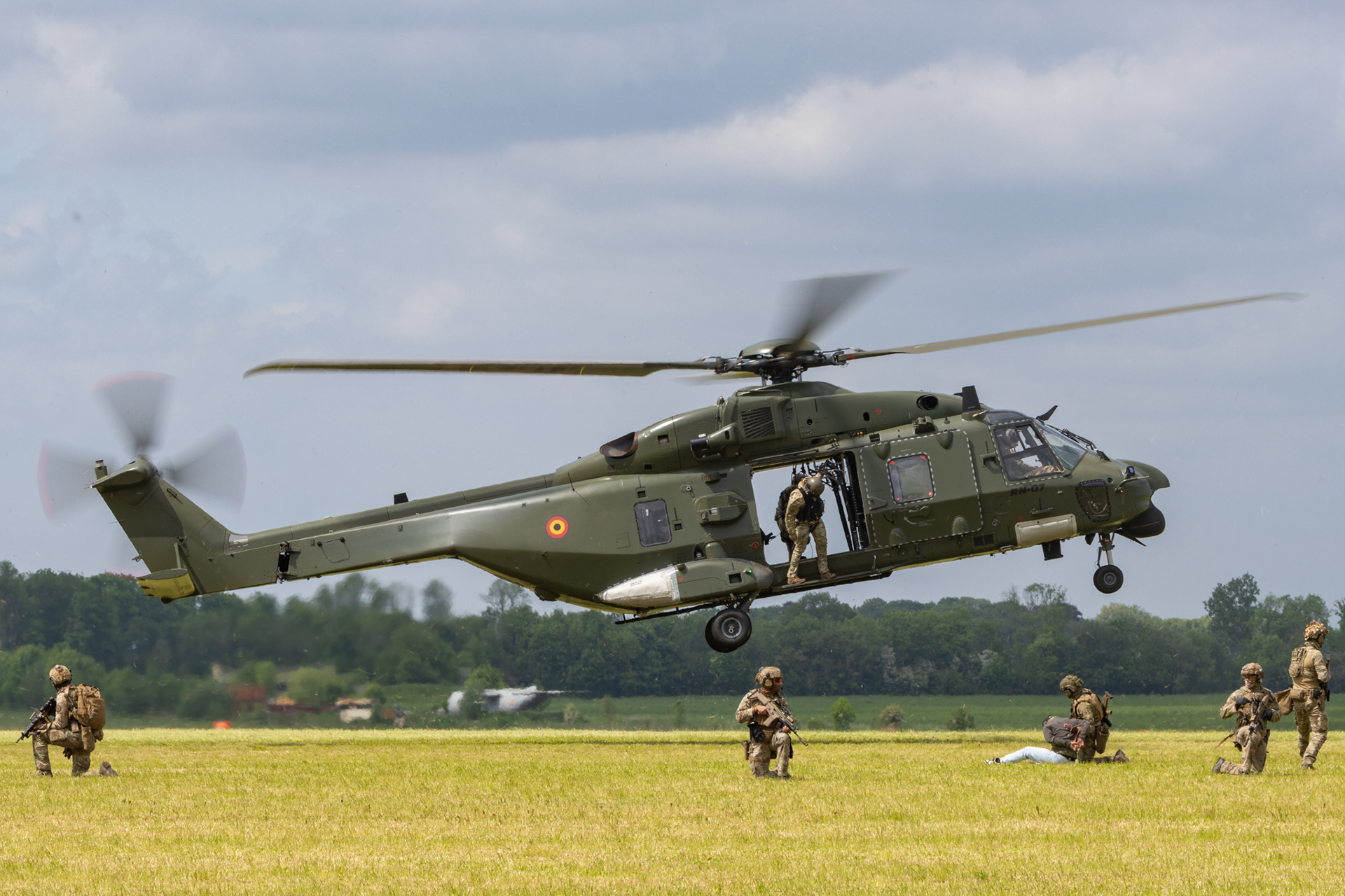Belgische NH-90 helikopter zet soldaten af op een veld tijdens een tactische oefening.