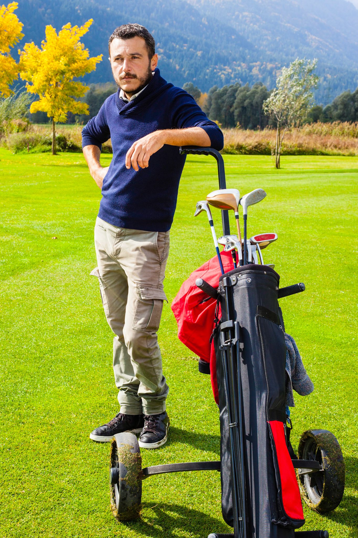 a golf player playing on a beautiful golf course and a golf bag full of golf clubs