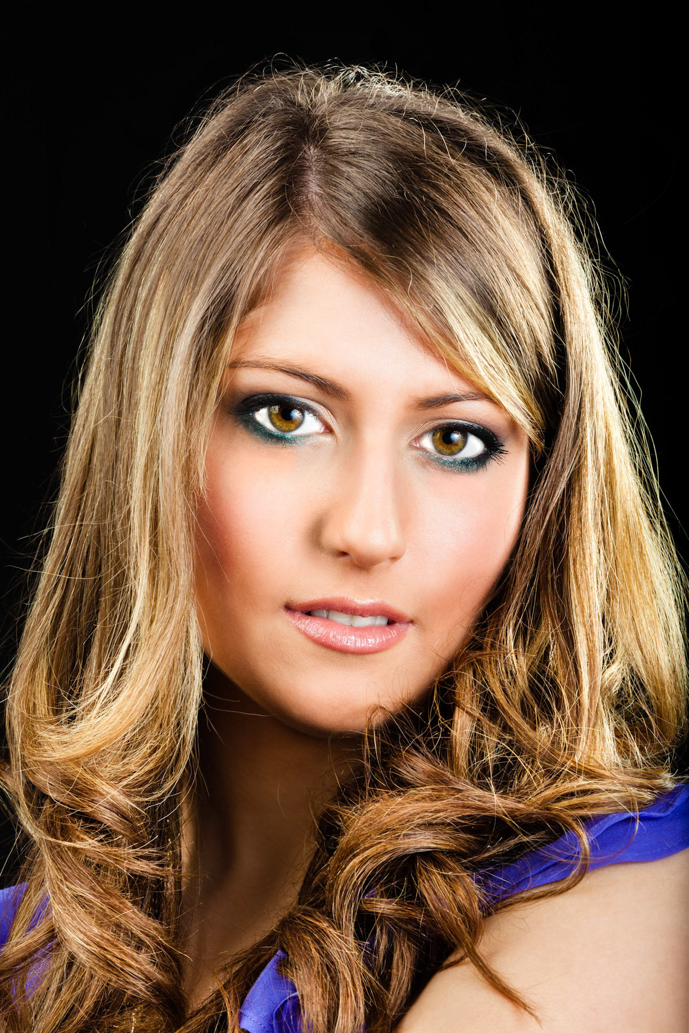A very beautiful woman in a dress and wearing jewelery posing on a black background