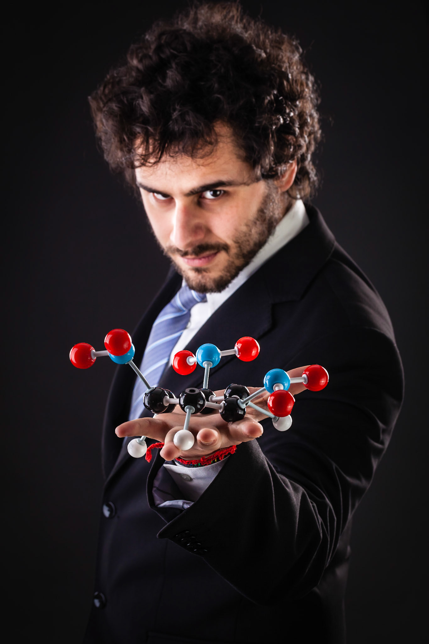 a businessman wearing a suit and a tie holding a trinitrotoluene tnt molecular model
