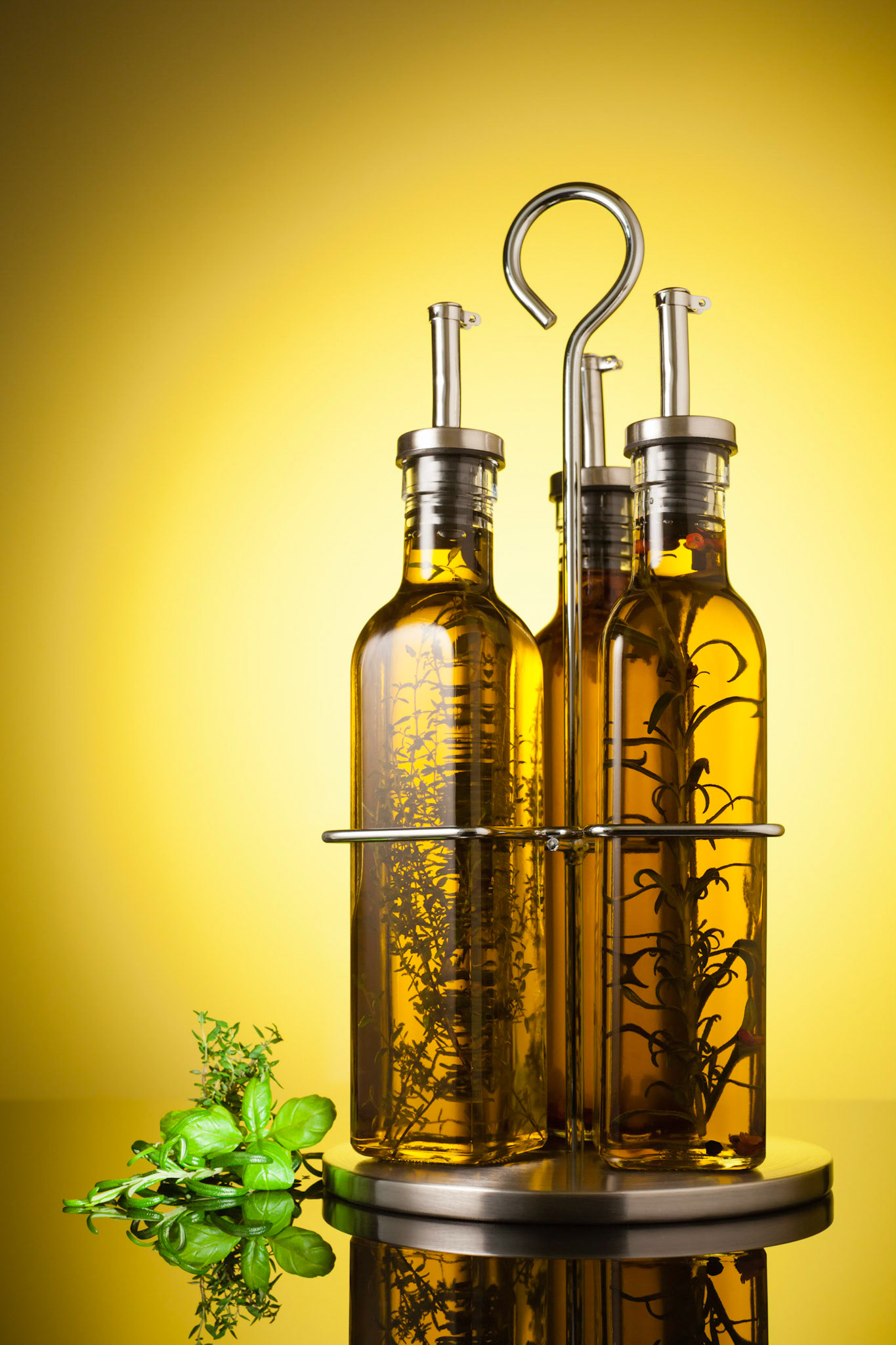 Studio shot of a Homemade olive oil bottle set with spices and herbs (rosemary, peppers, basil, thyme).