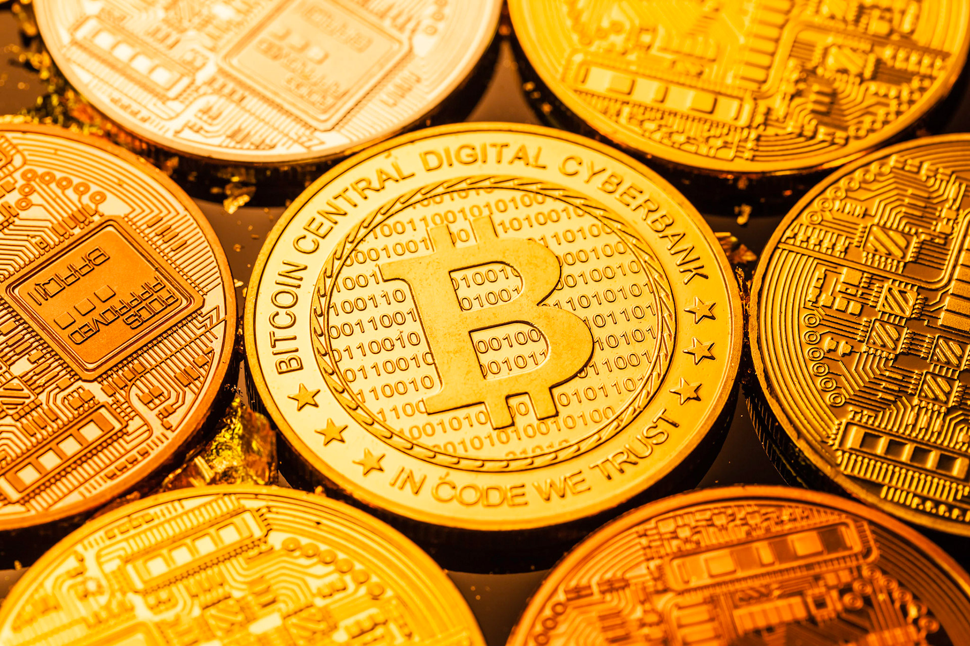 Studio shot of multiple bitcoin physical golden coins on a dark background with gold flakes. Bitcoin is a blockchain crypto currency