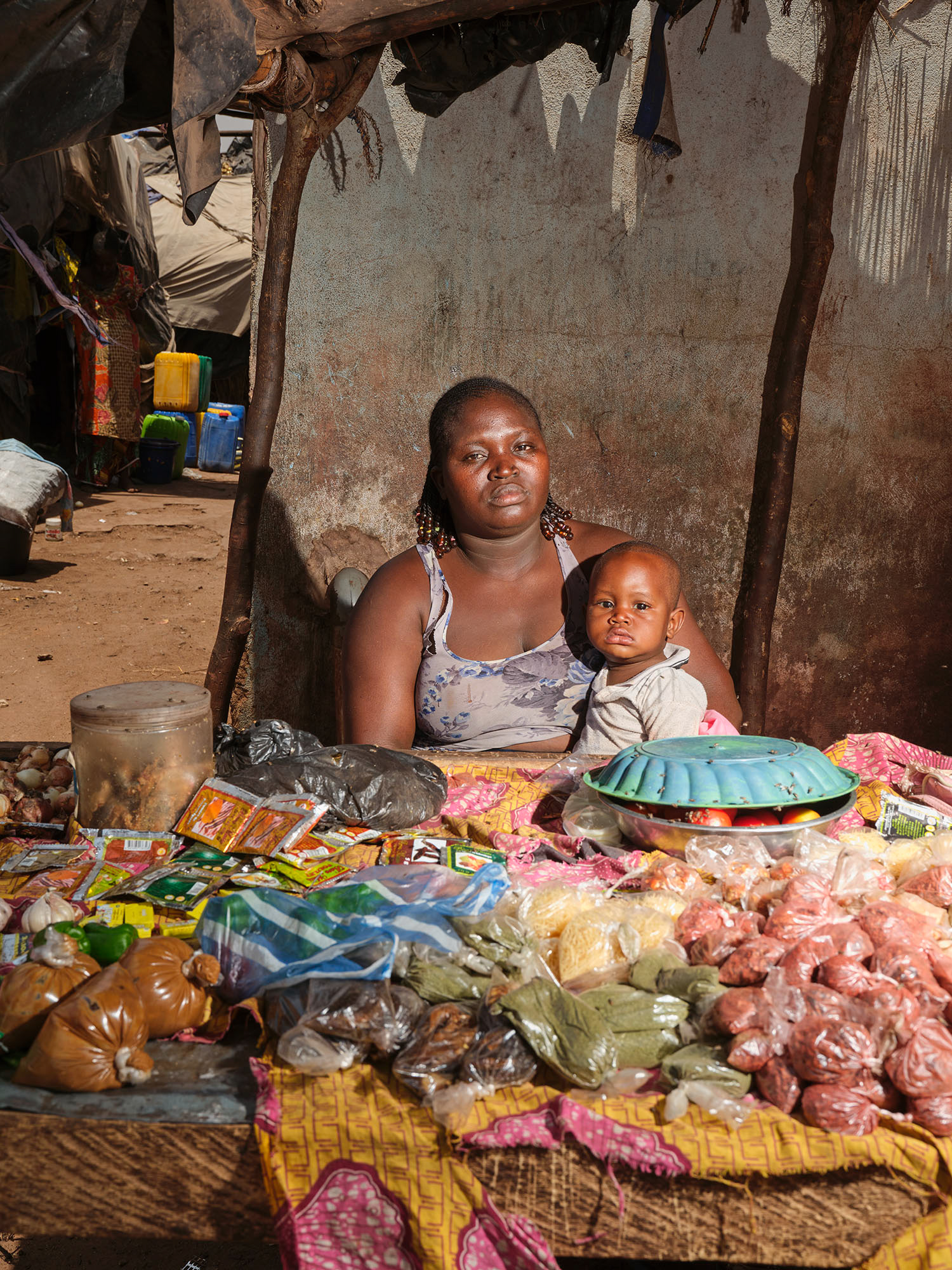 Rebeka Fojo and her son live in the Faladié displacement site, located on top of a garbage dump. She has a small stall where she sells food inside the site. Bamako, May 2025