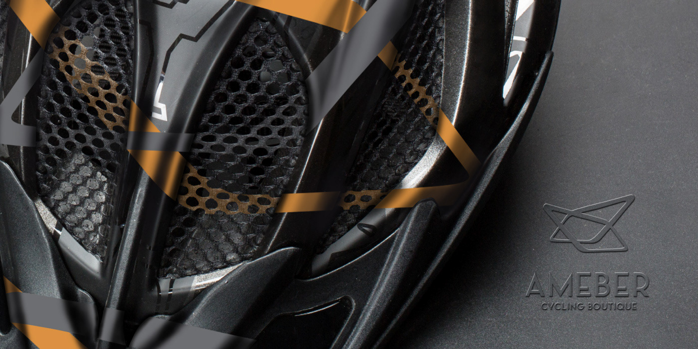 Detail shot of black cycling helmet with orange and black accents and Ameber Cycling Boutique logo