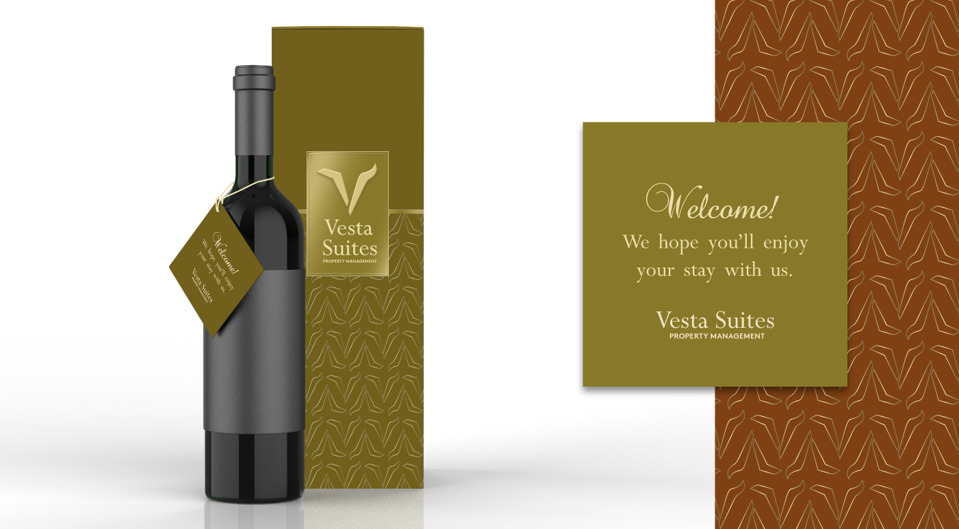 Wine bottle with gift tag that says welcome, gold packaging box with Vesta Suites logo pattern