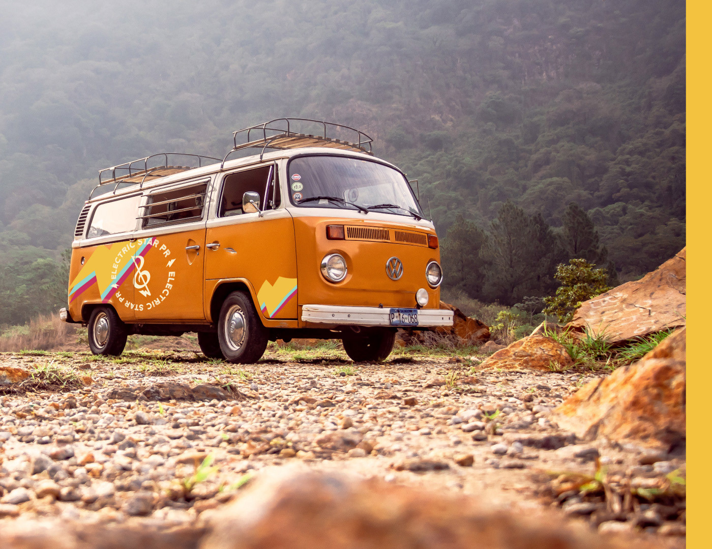 Orange vintage camper van with sticker design on a rocky mountain range