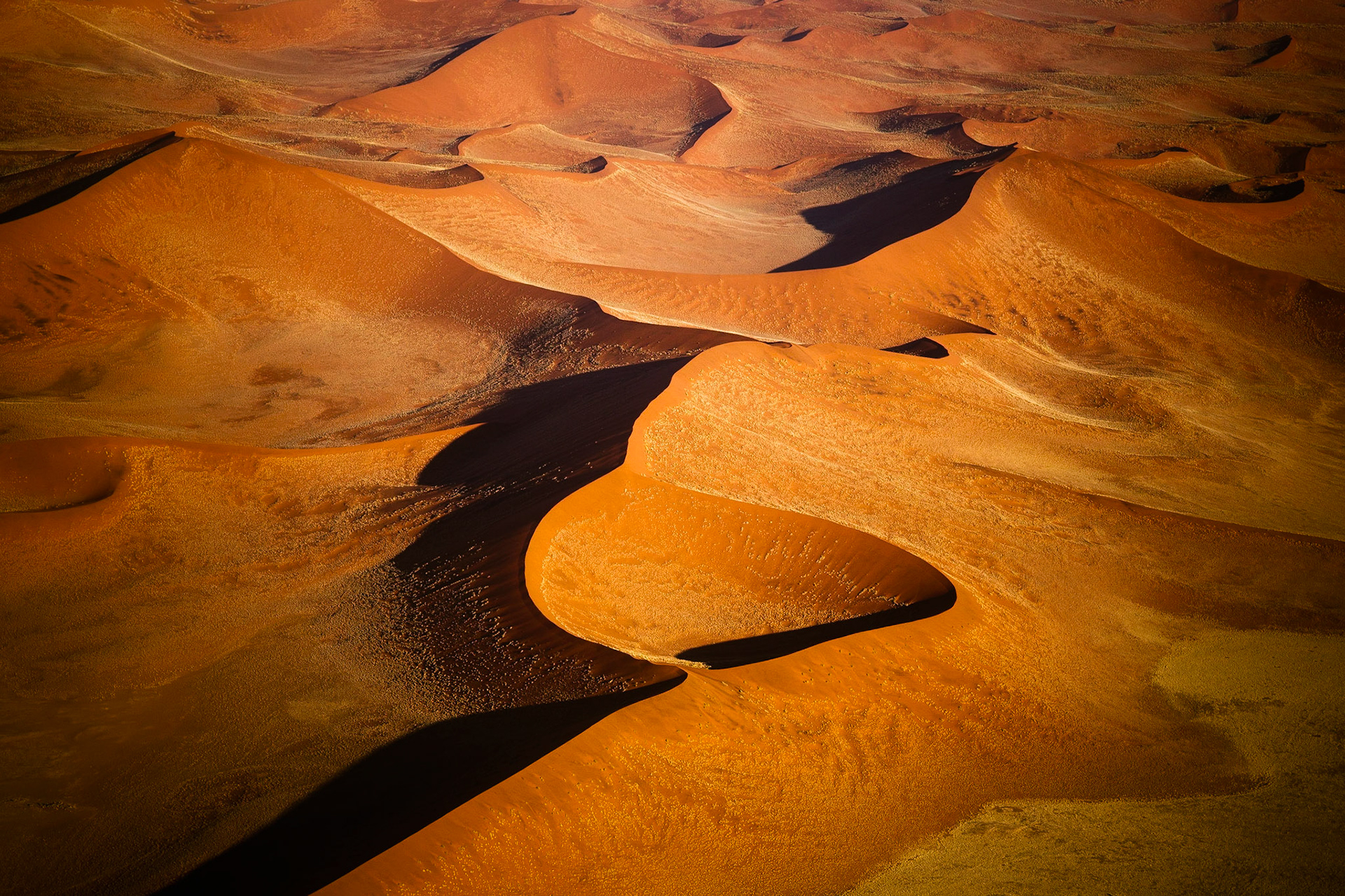 Pohled až na 300 metrů vysoké duny jedné z nejstarších pouští světa ze vzduchu odhalí, kolik tváří může mít písek v kombinaci se zapadajícím sluncem.