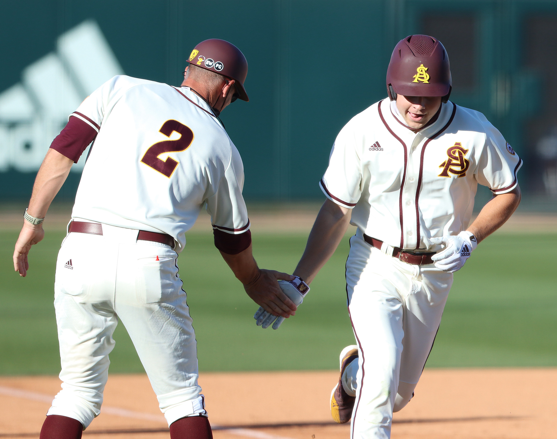 Arizona State pinch hitter Kade Higgins rounds third base and is greeted by coach Ben Greenspan after hitting a home run during a game on March 2, 2021, at Phoenix Municipal Stadium.