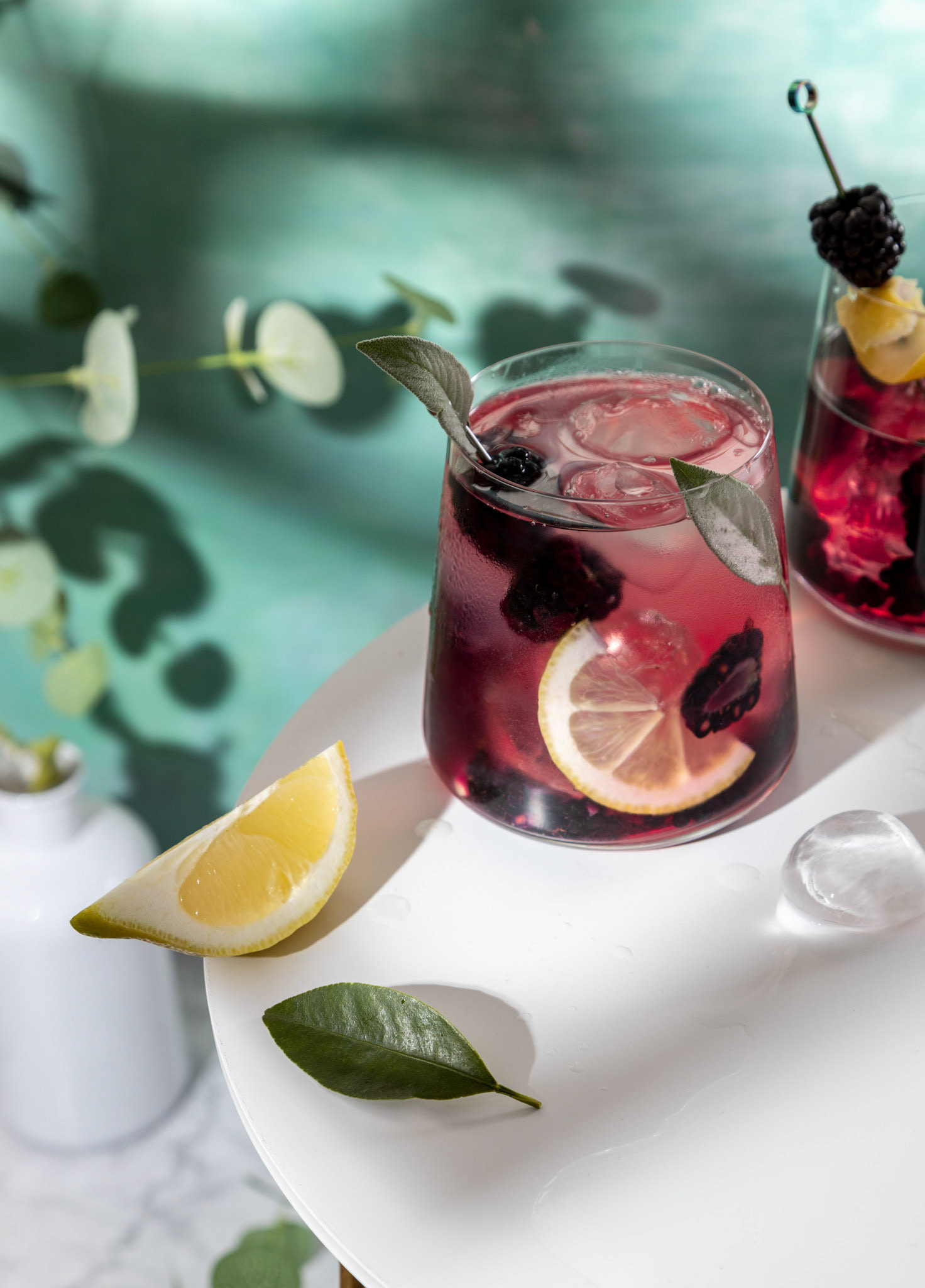 Blackberry cocktail . Berry cocktails in glass with ice and lemon on the white table .