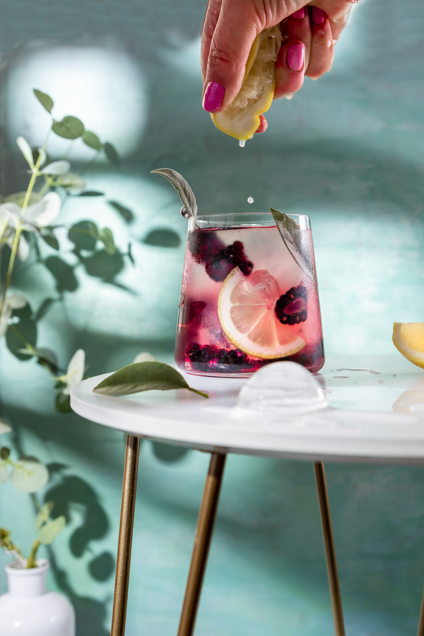 Blackberry cocktail . Berry cocktails in glass with ice and lemon on the white table .