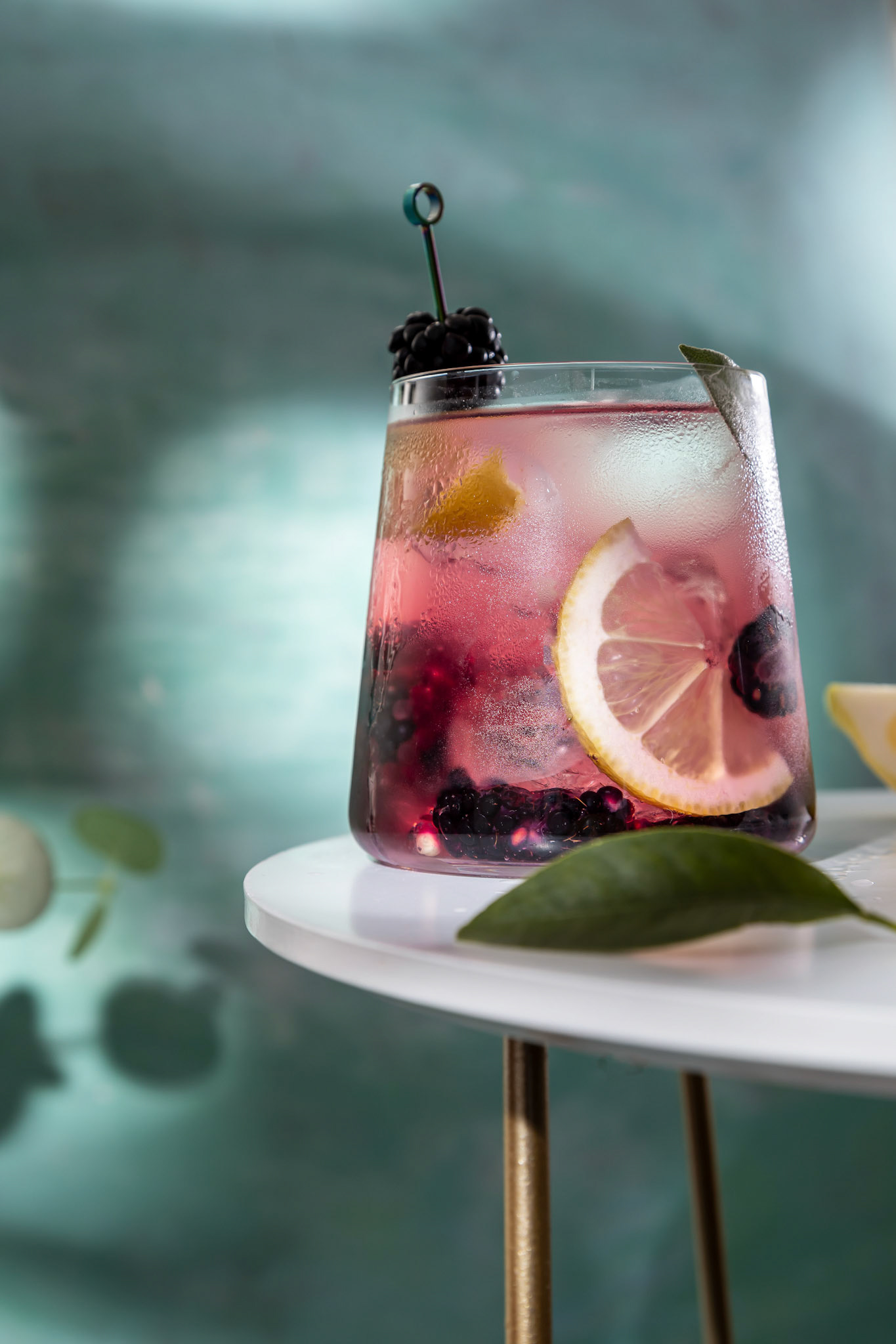 Blackberry cocktail . Berry cocktails in glass with ice and lemon on the white table .