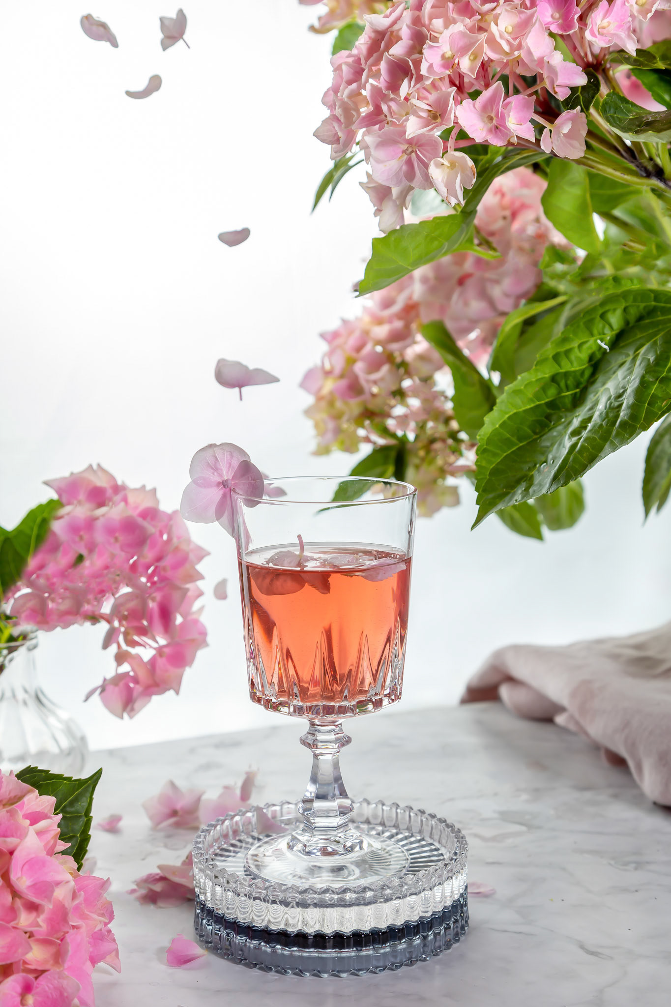 Wine Glass Pink Flowers Decor Background with flying petals , summer time .