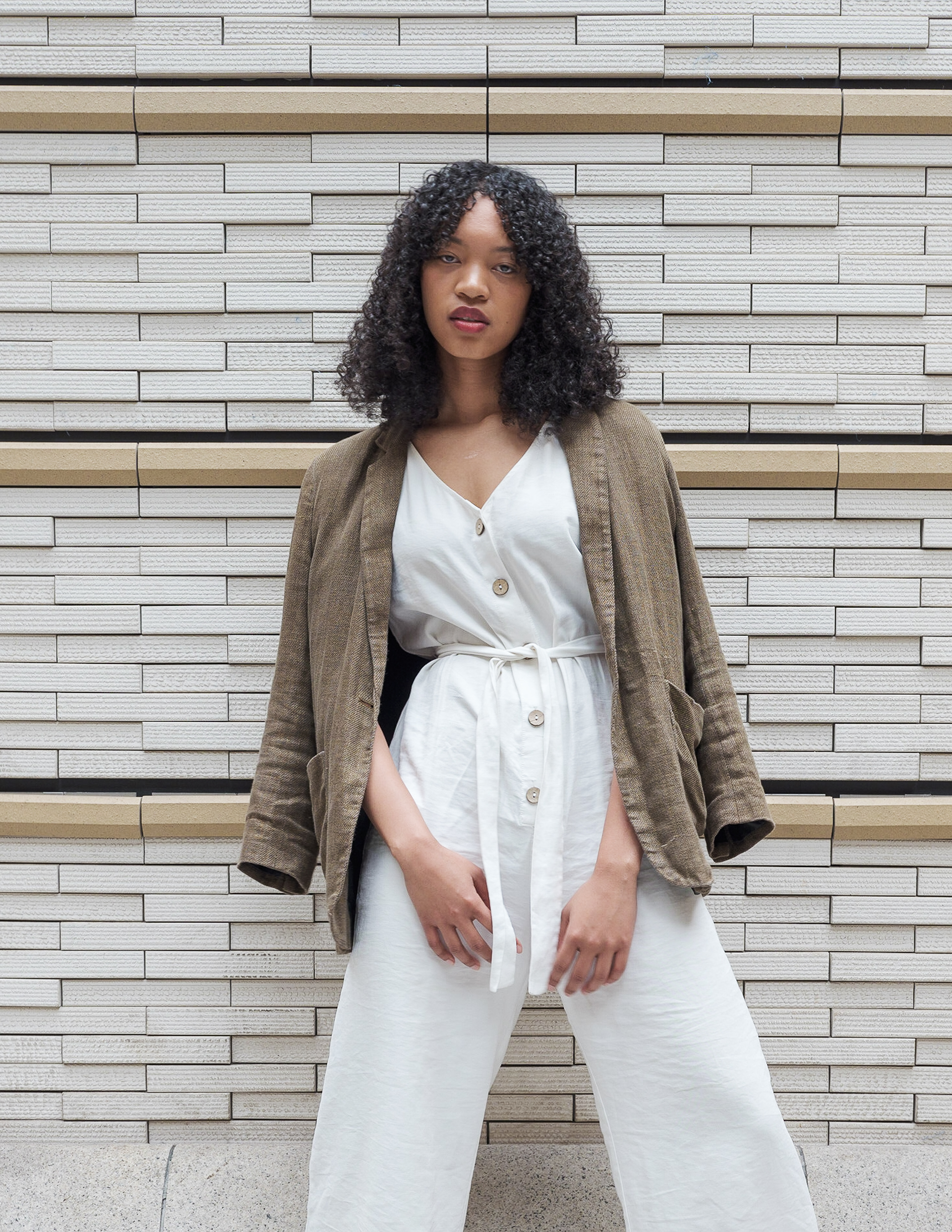 Ikeji Uju: Emily Osas elegantly adorned in a brown linen coat and white one-piece dress, set against the backdrop of Tokyo, Japan. Ikeji Uju Photography