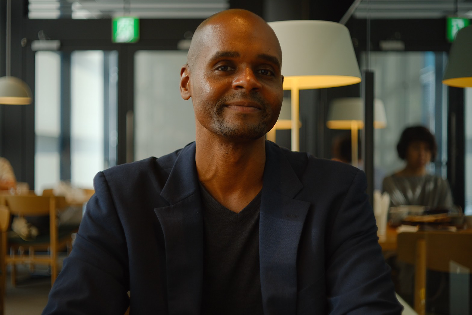 Photo of Ikeji Uju in a Shibuya, Tokyo, Japan restaurant stylishly wearing a blue suit and black v neck shirt. Photo taken by Benjamin Michel.