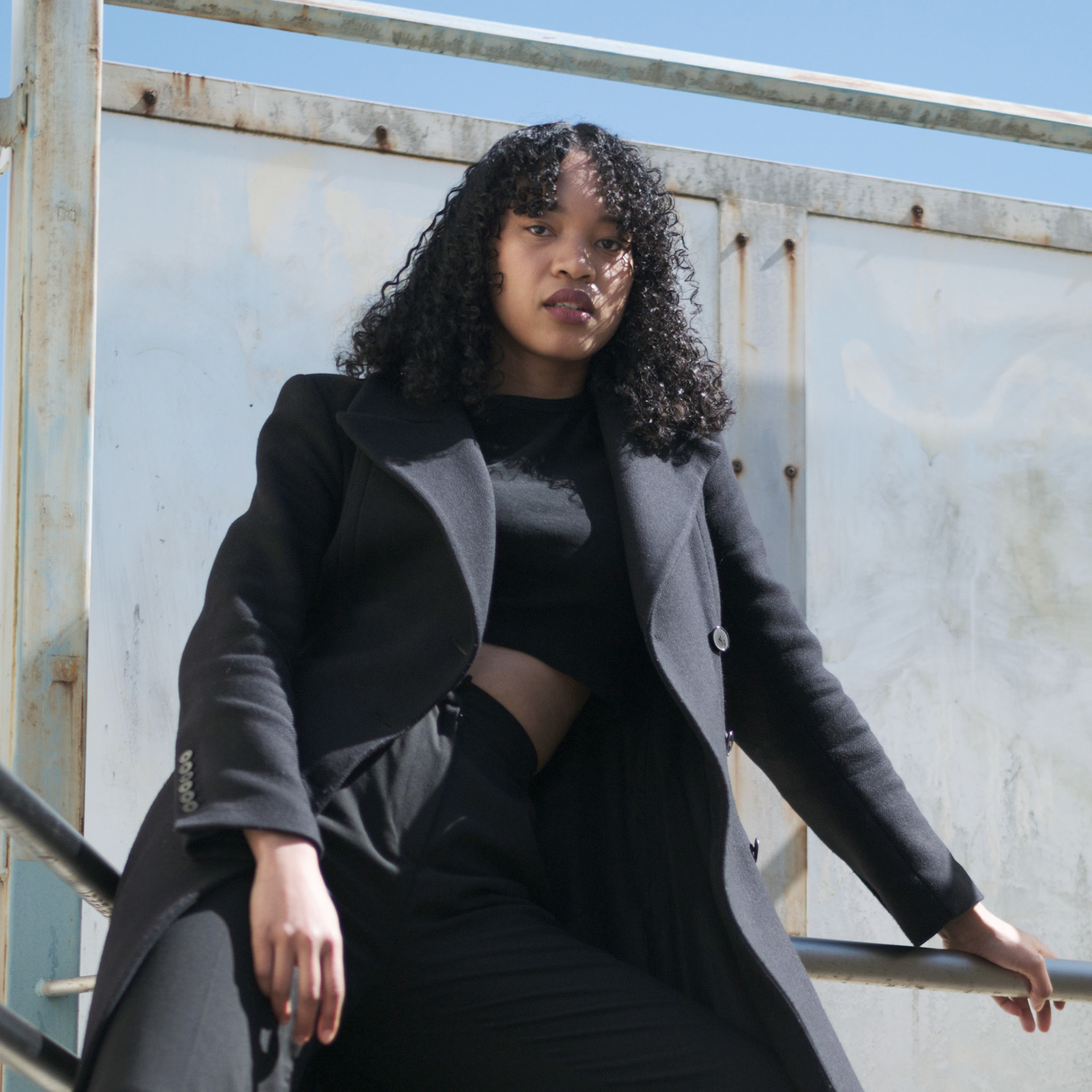 Ikeji Uju:  Emily Osas, a stunning mixed Japanese model elegantly adorned in a black crop top, black long pants, and black long coat set against the backdrop of Nakameguro City, Tokyo, Japan. Ikeji Uju Photography